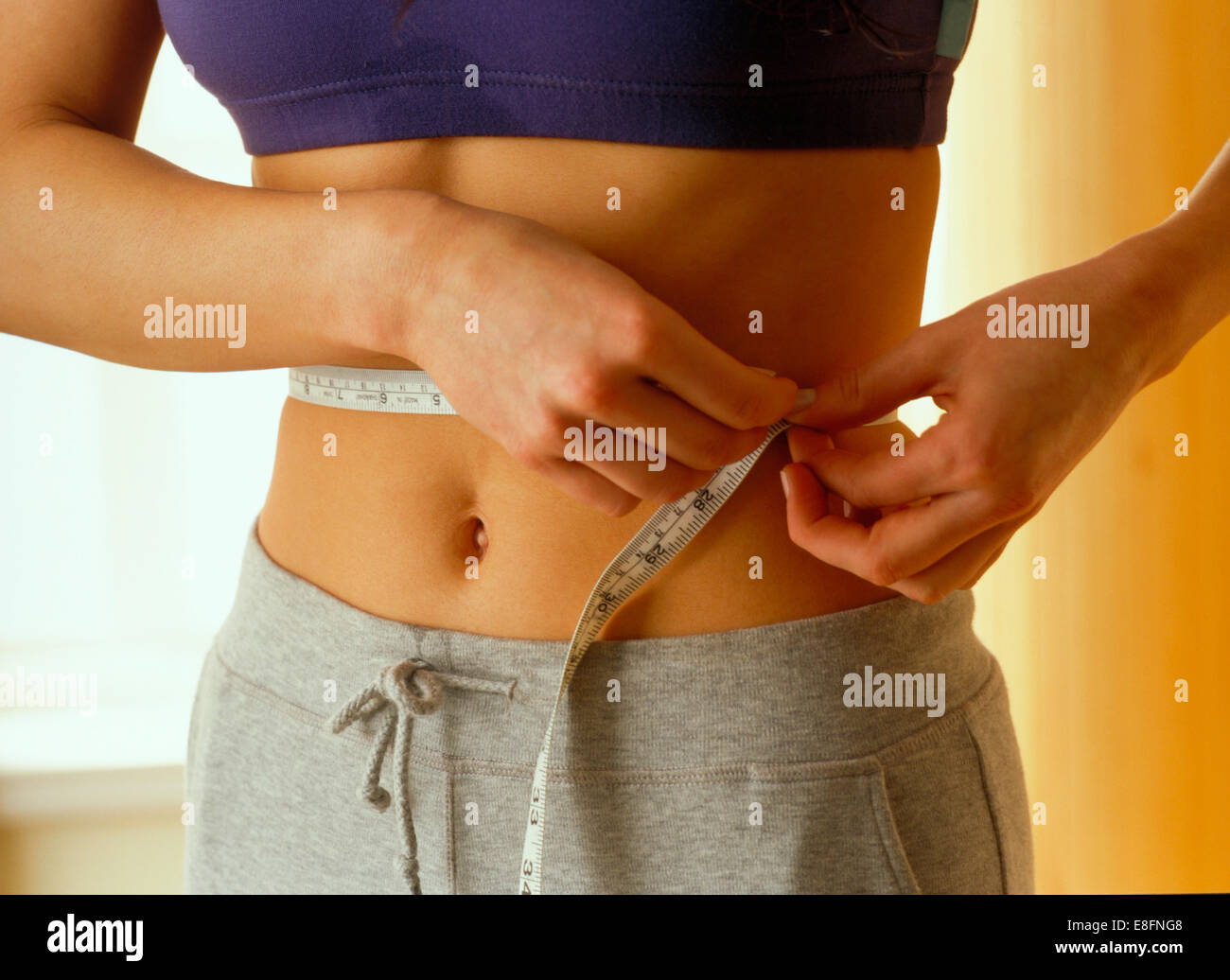 Nahaufnahme einer Frau messen ihre Taille mit einem Maßband Stockfoto