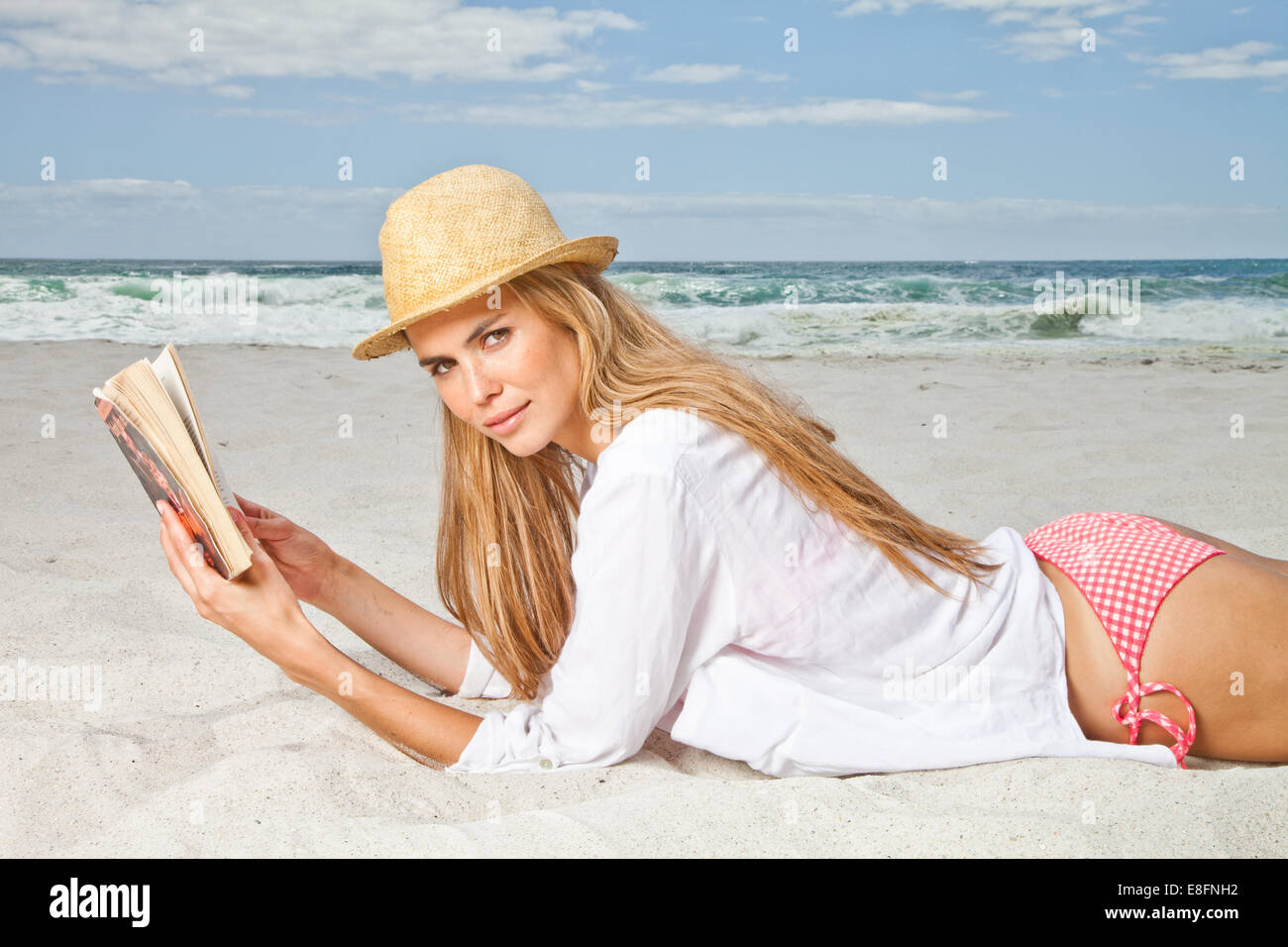 Junge Frau, die ein Buch am Strand, Kapstadt, Westkap, Südafrika liest Stockfoto