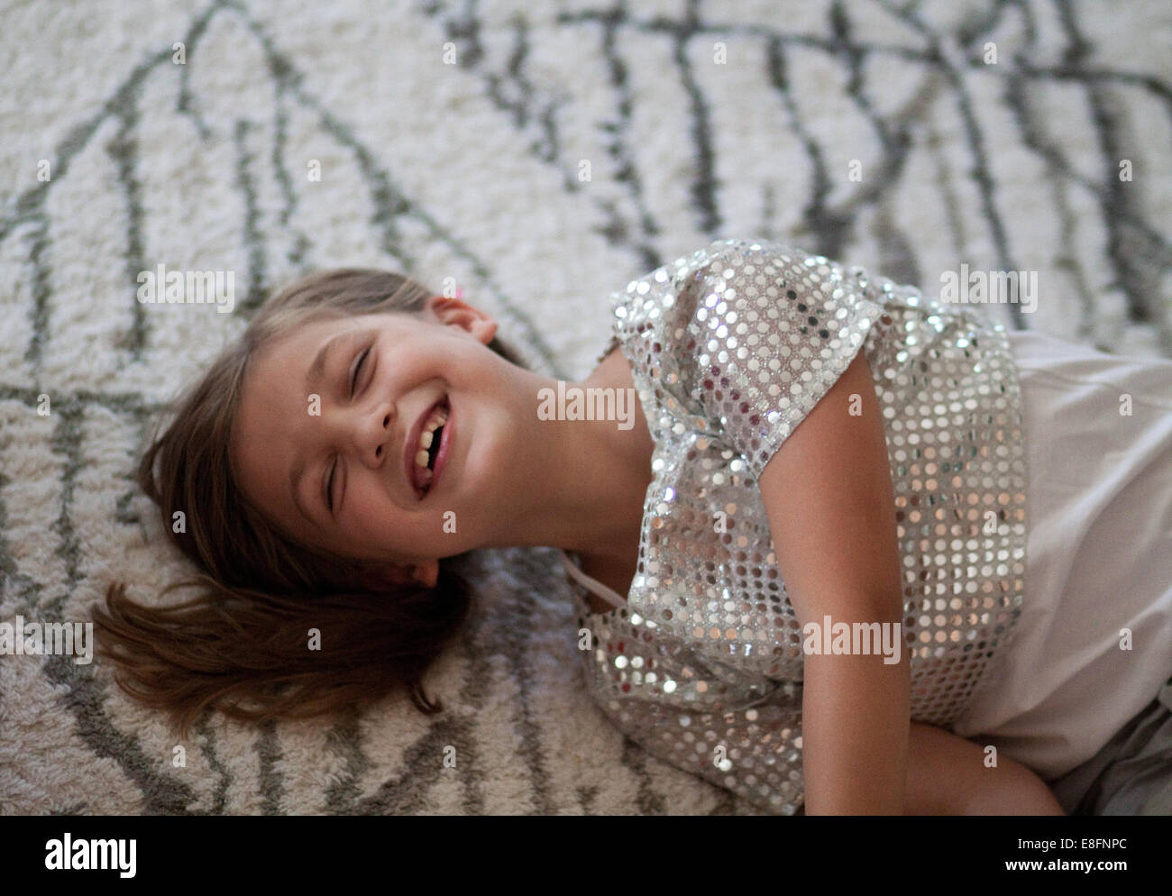 Lächelndes Mädchen liegend auf Teppich Stockfoto