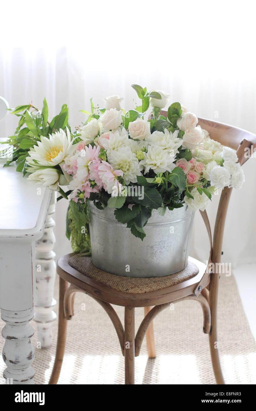 Eimer mit Blumen auf Stuhl Stockfoto