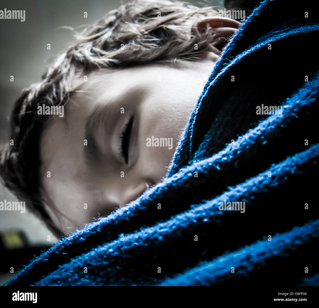 Nahaufnahme eines Jungen, der unter einer blauen Decke schläft Stockfoto
