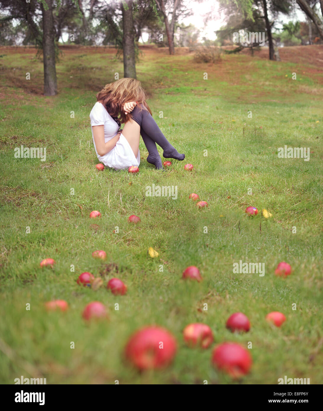 Frau sitzt in einem Garten neben gefallenen Äpfeln, Spanien Stockfoto