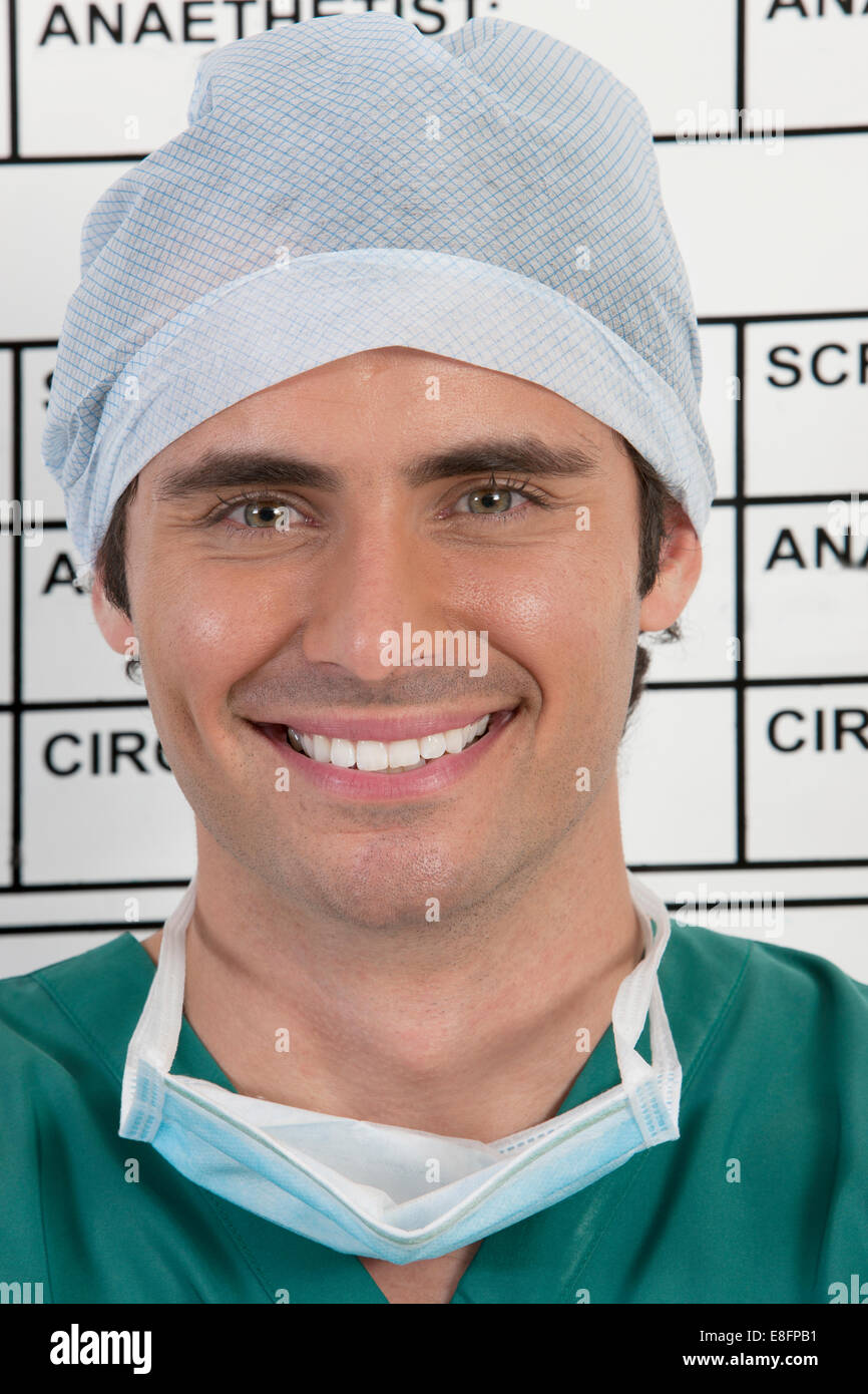 Porträt des lächelnden Chirurgen vor Zeitplan Board im Krankenhaus Stockfoto