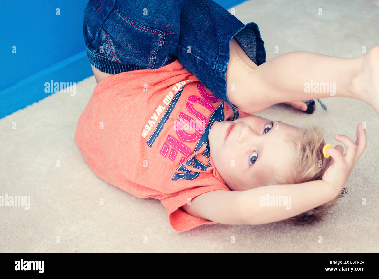 Boy am Boden auf dem Kopf stehend mit Spielzeug spielen Stockfoto