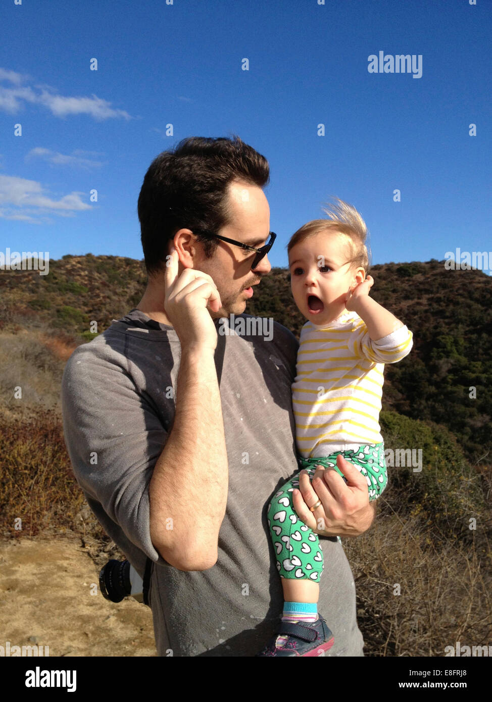 Vater und Tochter (18-23 Monate) Hand in Hand zu Ohren hören Stockfoto