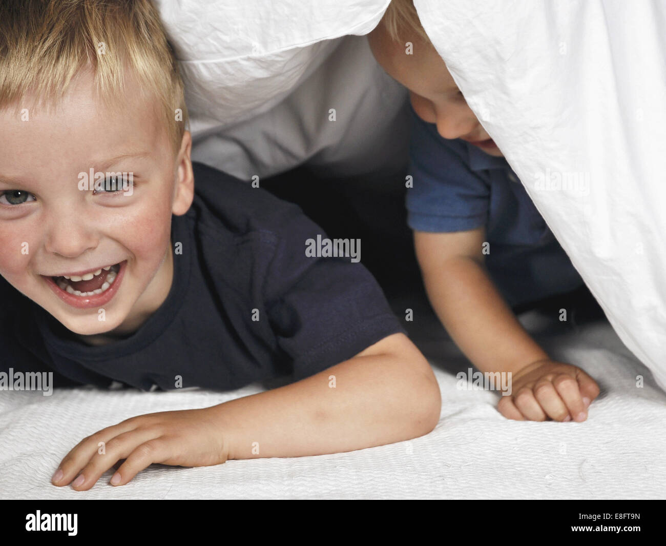 Zwei Jungen versteckt sich unter einer Bettdecke Stockfoto