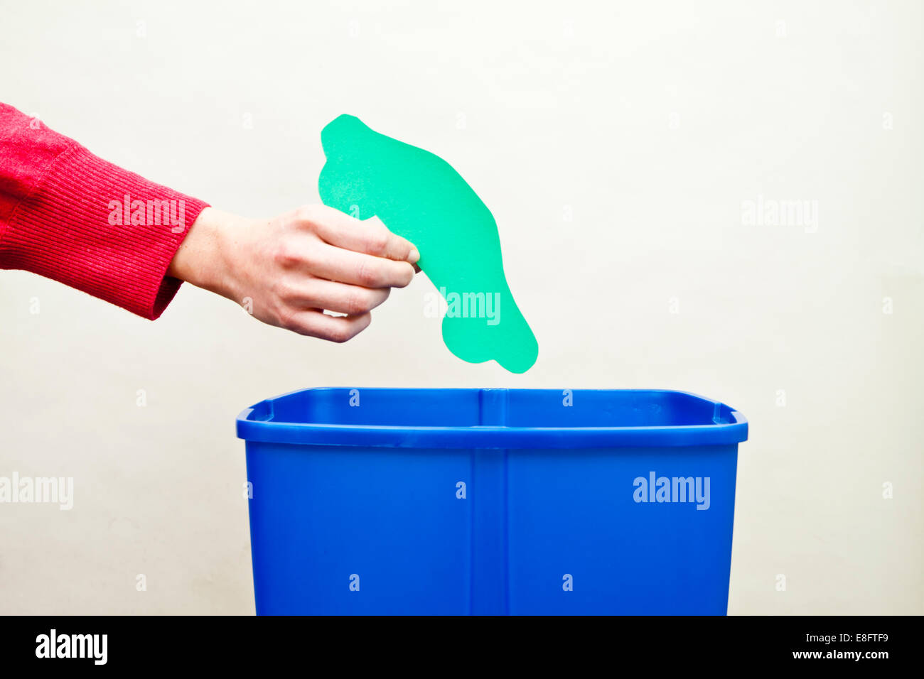 Zarte Frauenhand fallen Auto Form Papier ausgeschnitten in Recyclingbehälter Stockfoto