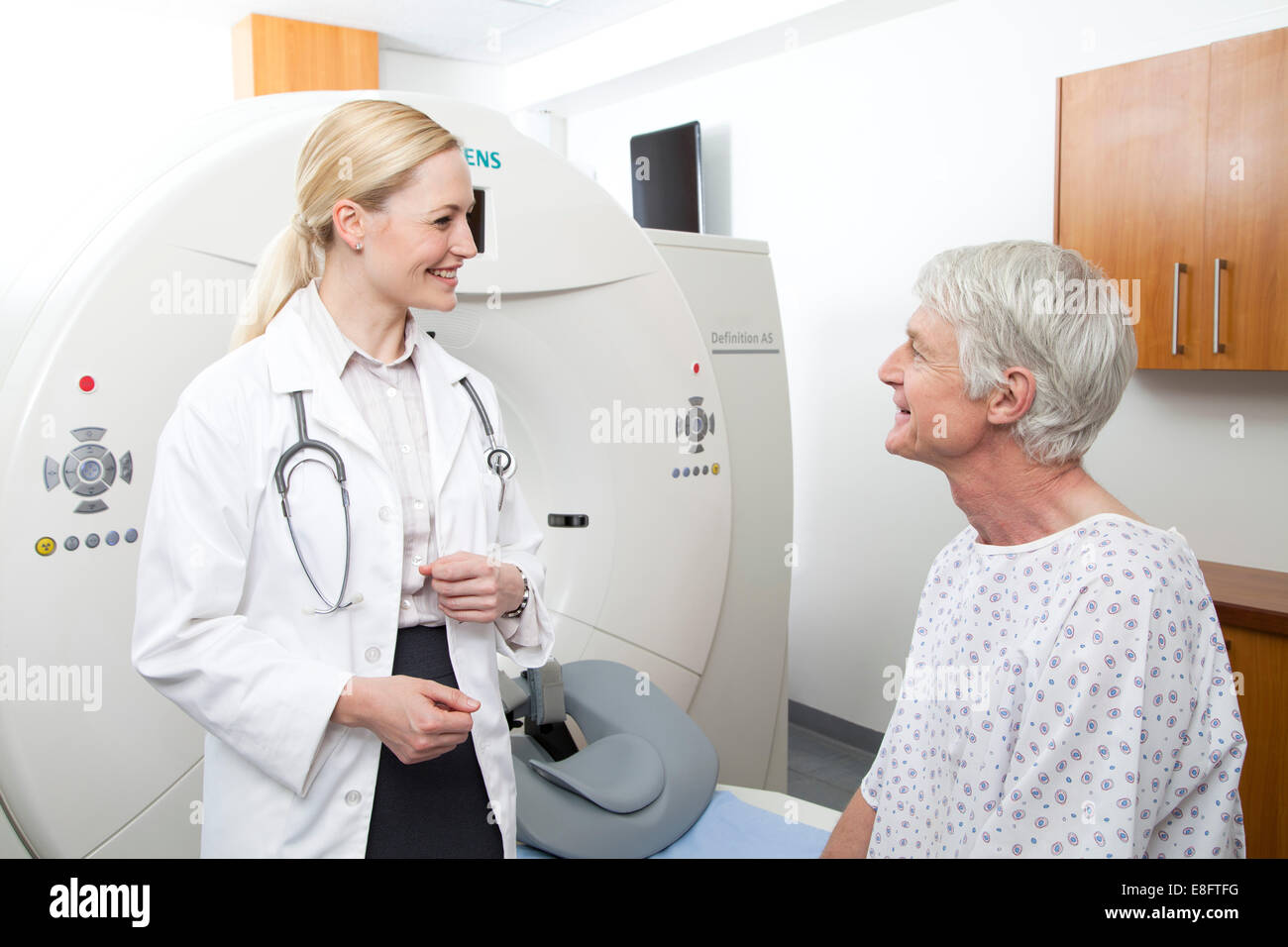 Weiblich-Arzt im Gespräch mit männlichen Patienten neben MRI Scanner Stockfoto