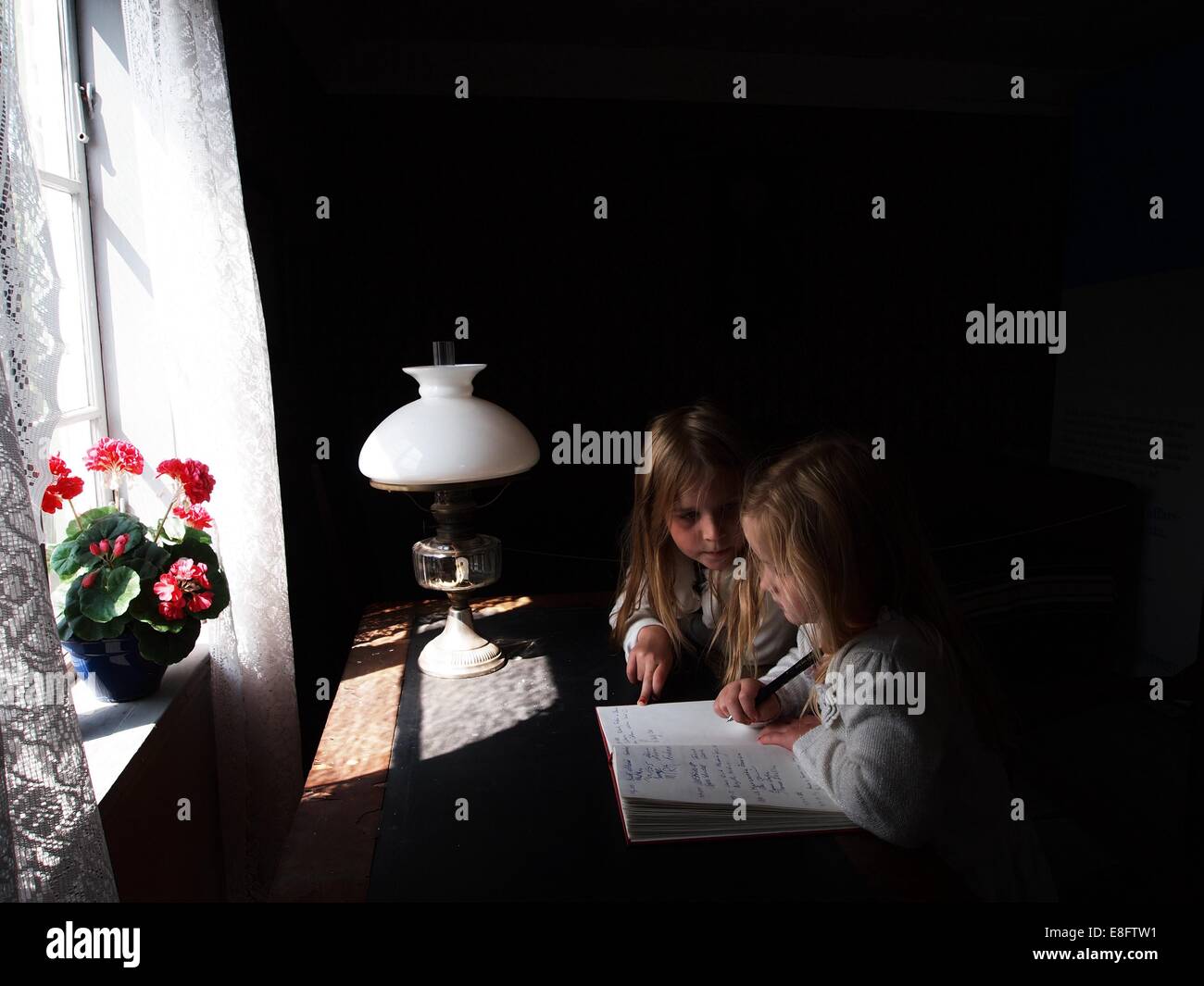 Zwei Mädchen sitzen an einem Fenster und lernen zusammen, Schweden Stockfoto