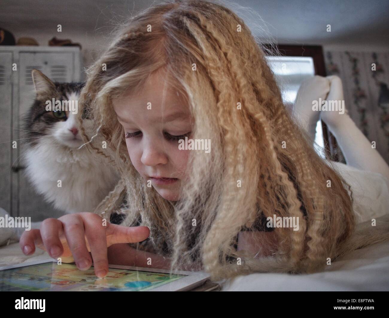 Mädchen, das mit ihrer Katze auf einem digitalen Tablet liegt, Schweden Stockfoto