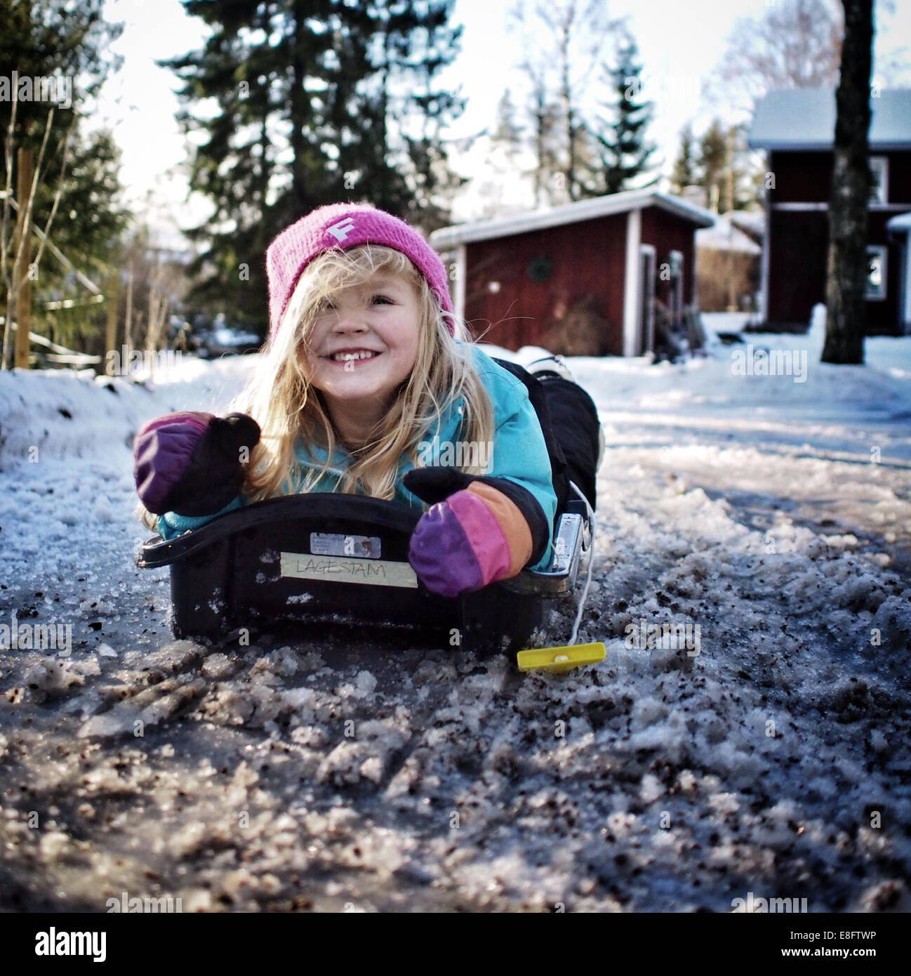 Mädchen auf einem Schlitten im Schnee liegend, Schweden Stockfoto
