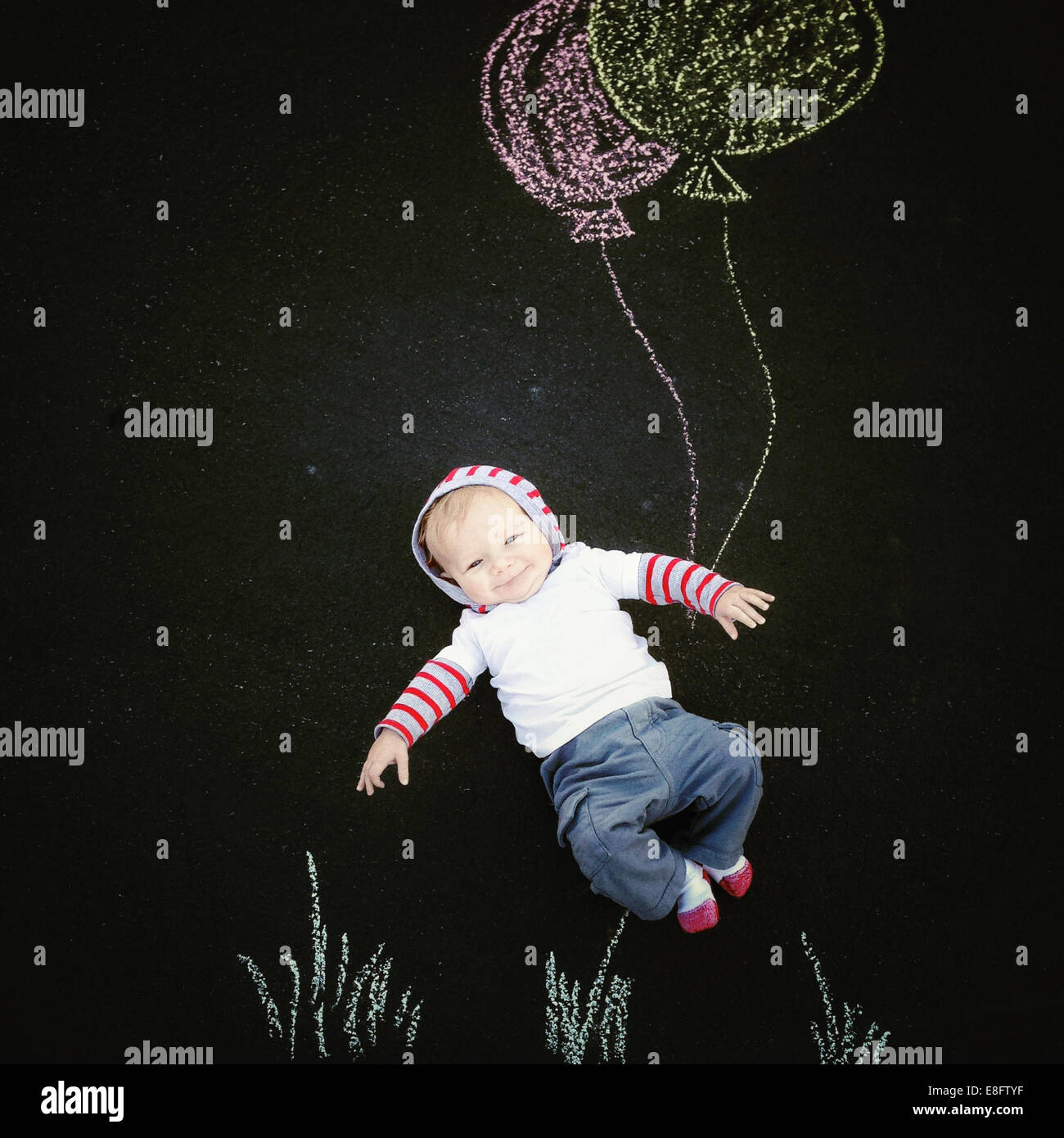 Lächelnder Baby Junge mit Kreidezeichnung von Ballons Stockfoto