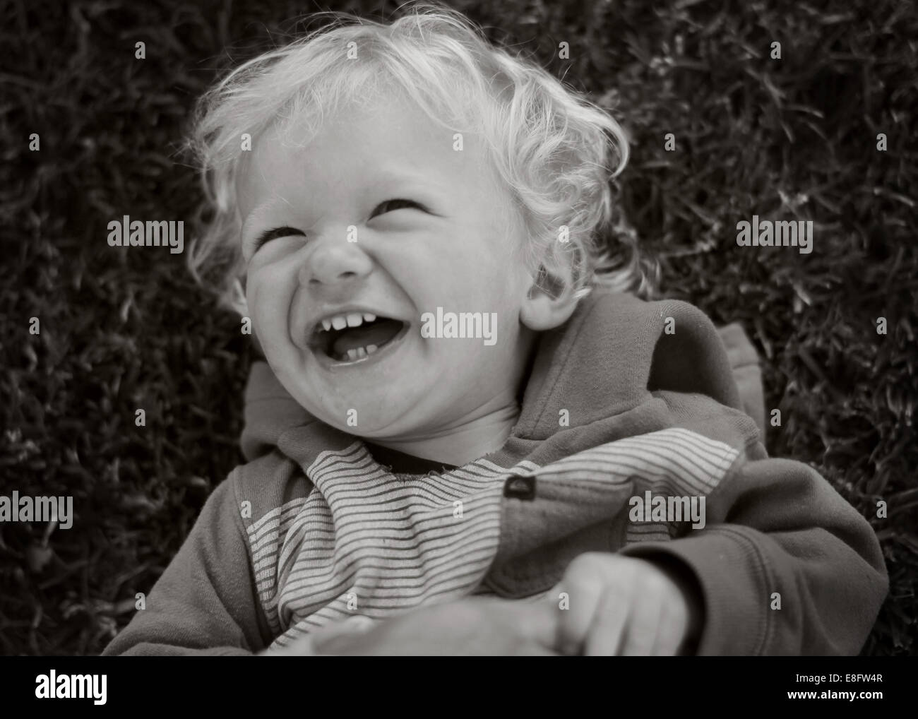 Kleinkind liegen auf Rasen vor Lachen Stockfoto