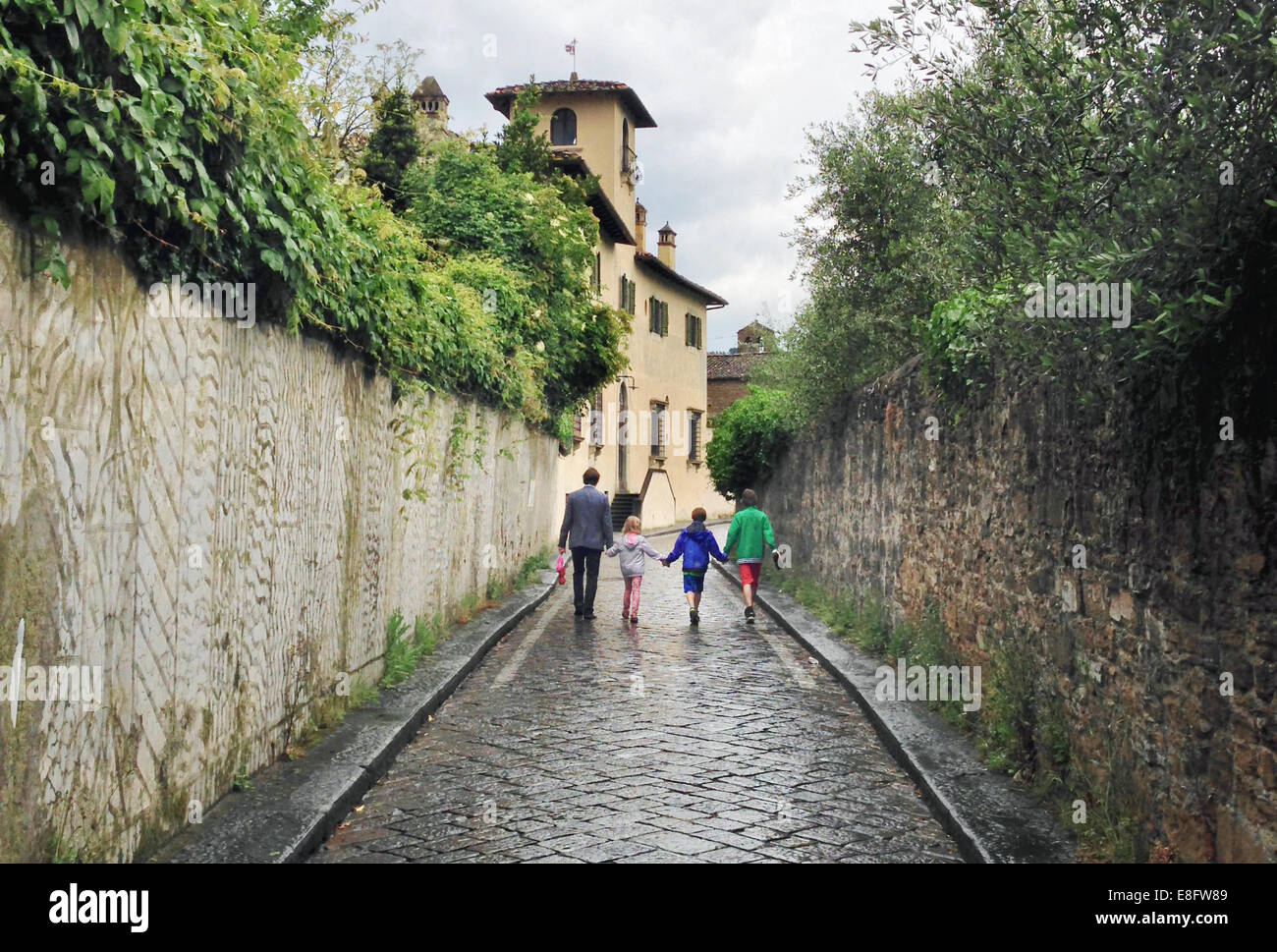 Vater und drei Kinder, die die Straße hinunter laufen, Florenz, Toskana, Italien Stockfoto