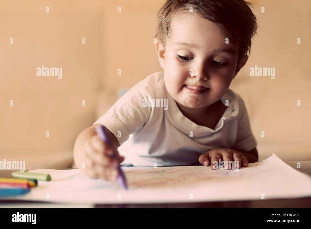 Junge sitzt am Tisch mit Buntstiften zeichnen Stockfoto