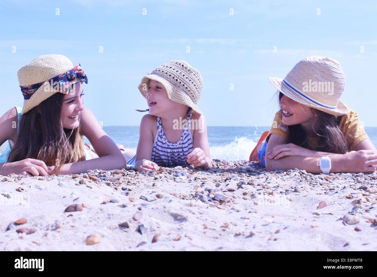 Drei Mädchen am Strand liegen an ihrer Vorderseite Stockfoto