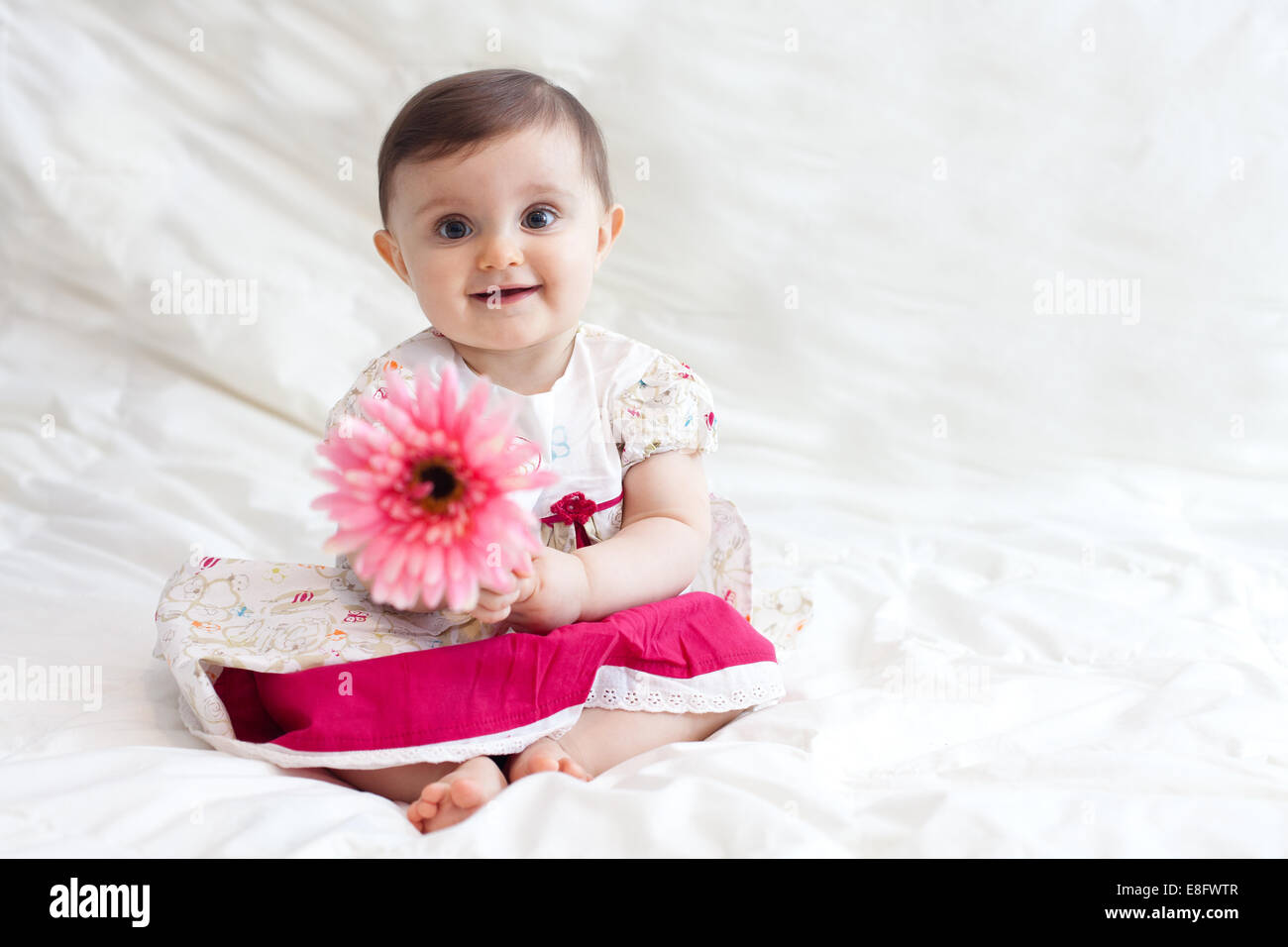 Lächelndes Mädchen, das eine Plastikblume hält Stockfoto