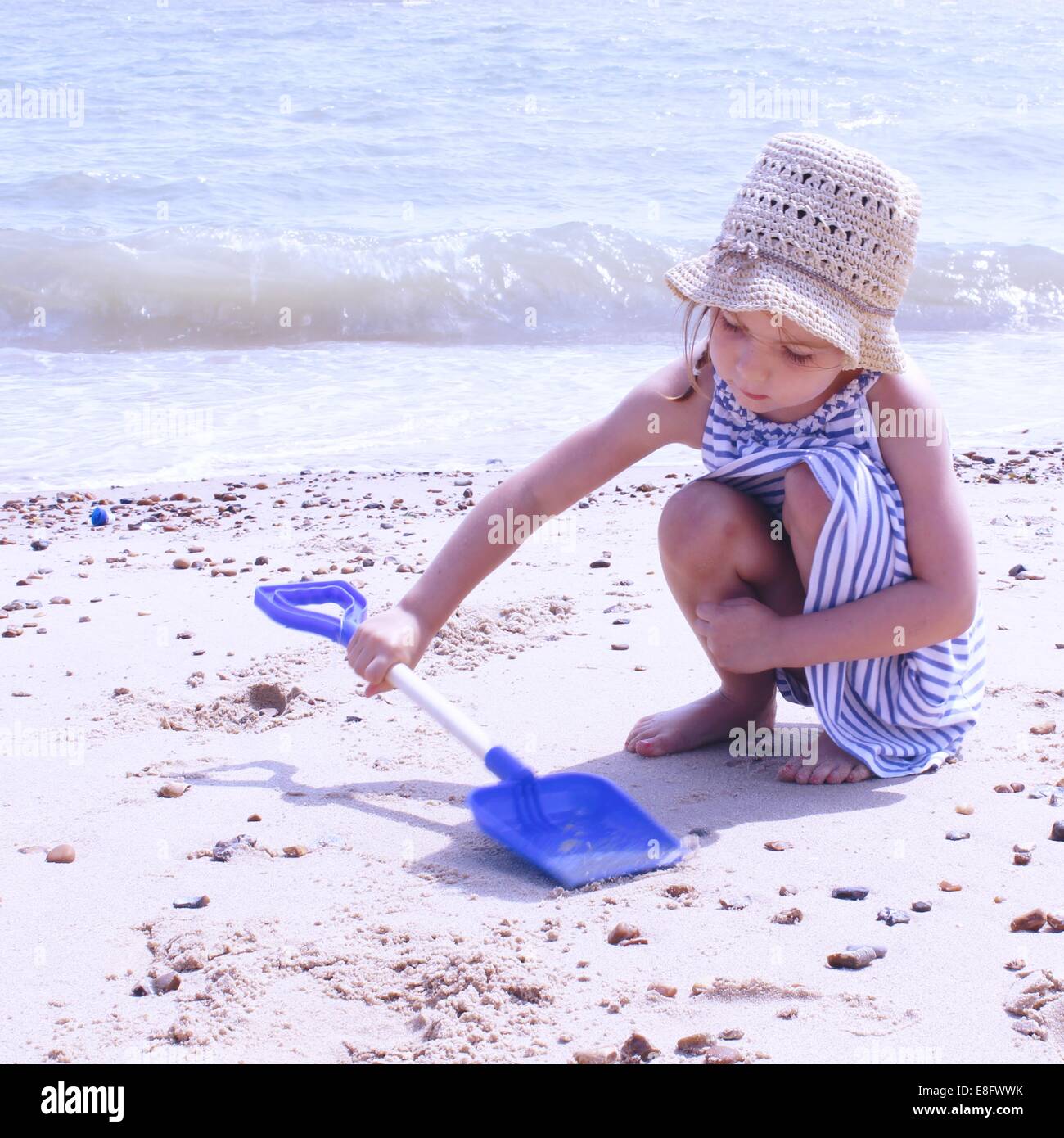Mädchen am Strand spielen mit Kunststoff Spaten hocken Stockfoto