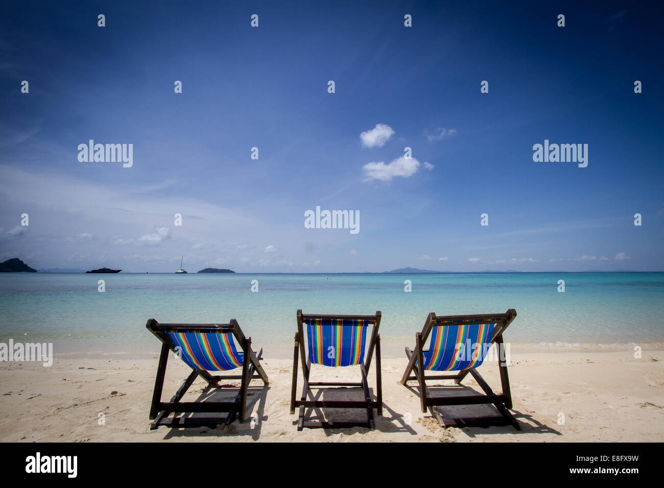 Drei Liegestühle in einer Reihe am Strand, Phuket, Thailand Stockfoto