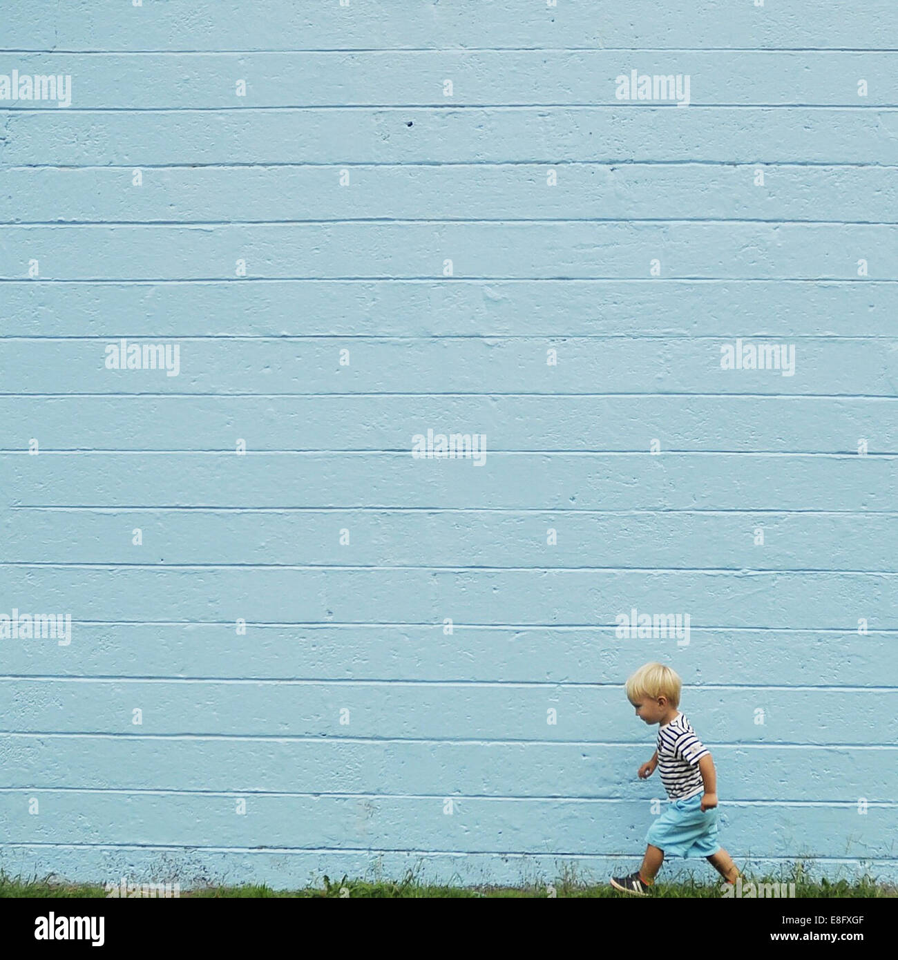 Junge, vorbei an einer blauen Wand Stockfoto