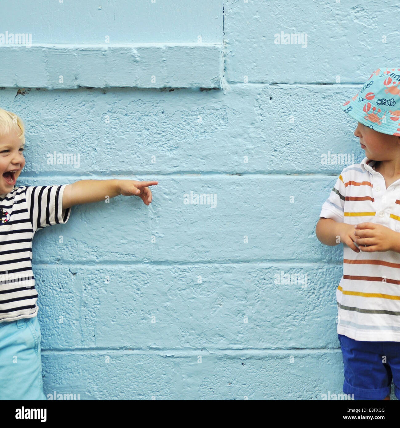 Zwei jungen, die vor einer blauen Wand Flickschusterei Stockfoto