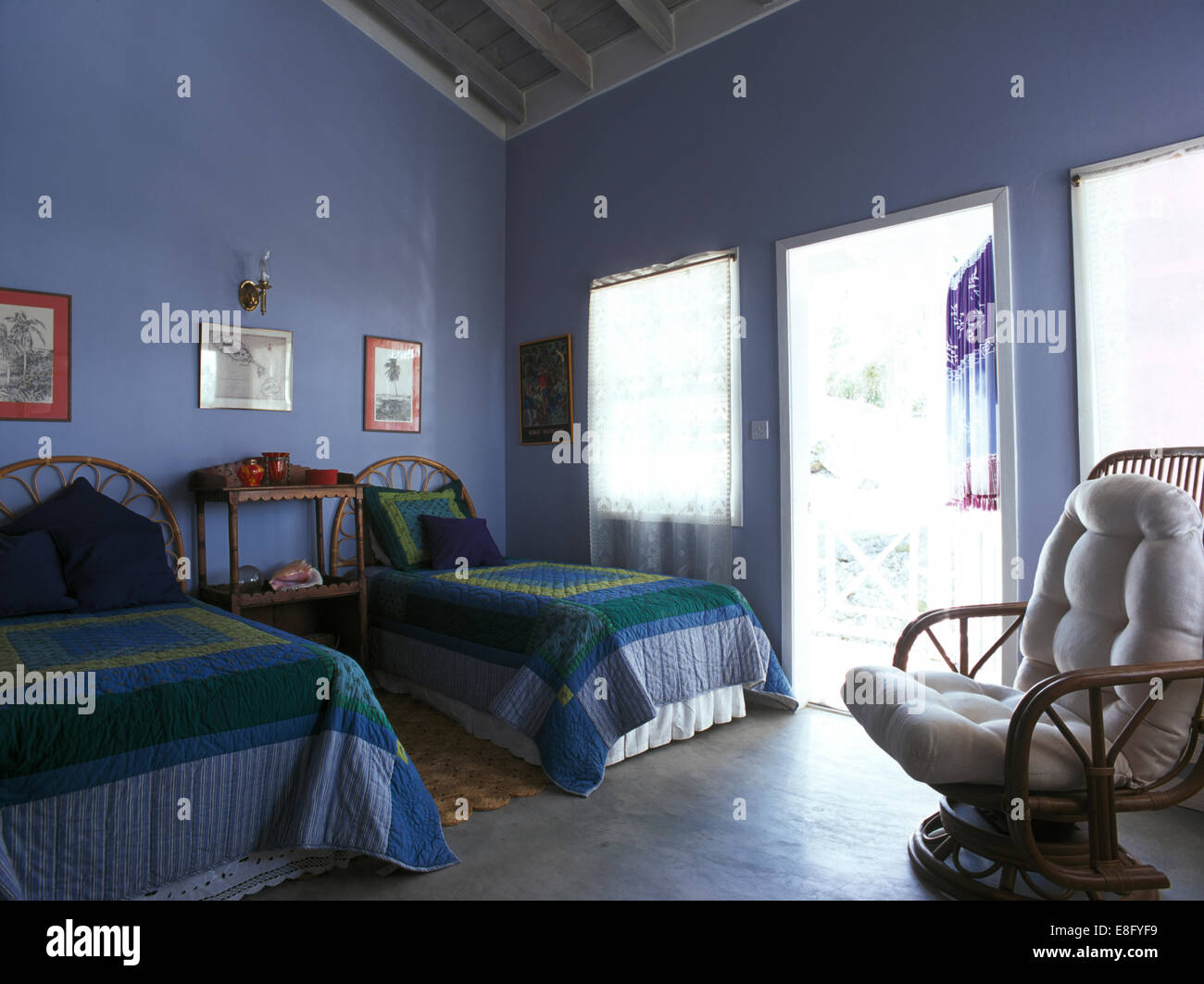 Blau + grün Patchwork quilts auf Einzelbetten im blauen Küste Schlafzimmer mit Zuckerrohr Sessel Stockfoto