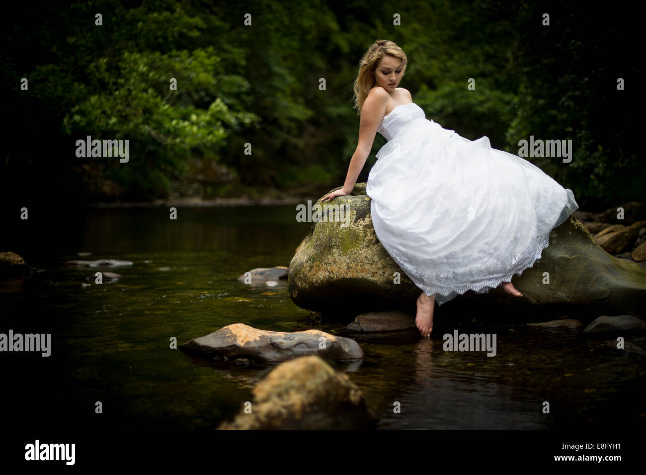 "Trash The Dress": eine junge blonde Frau Mädchen Modell "Braut" trägt eine weißes Ballkleid Brautkleid ihre Zehen in Fluss UK Stockfoto