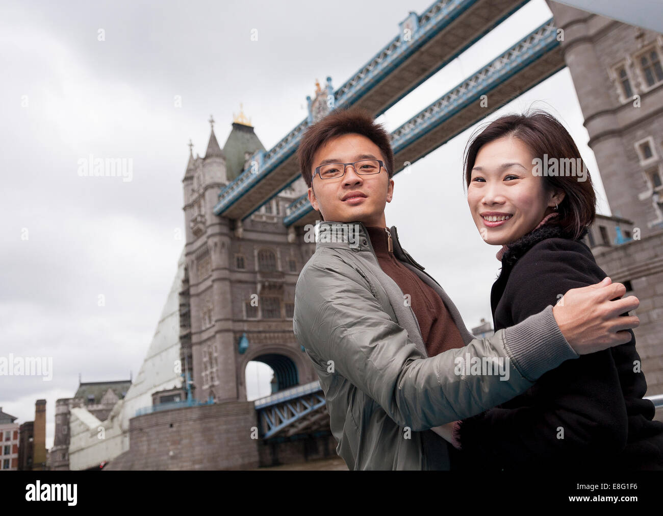 chinesische asiatische paar Besuch in London (aus Singapur) halten einander lächelnd vor der Tower Bridge Stockfoto
