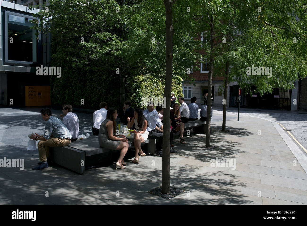 Leute sitzen im Schatten in London Mittagessen Stockfoto