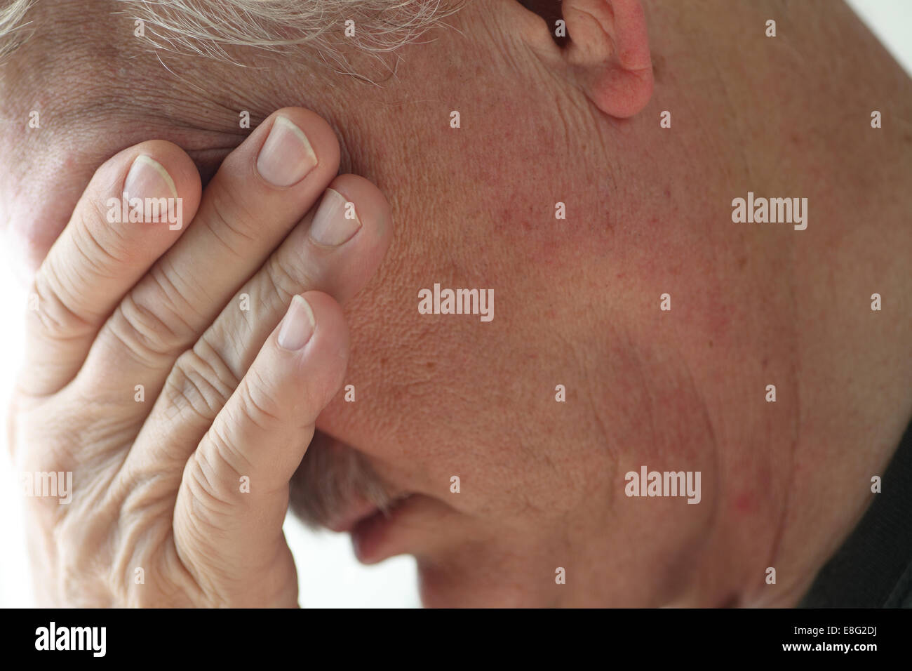 Depressive ältere Menschen bannt seinen Kopf, seine Augen mit der Hand bedecken. Stockfoto