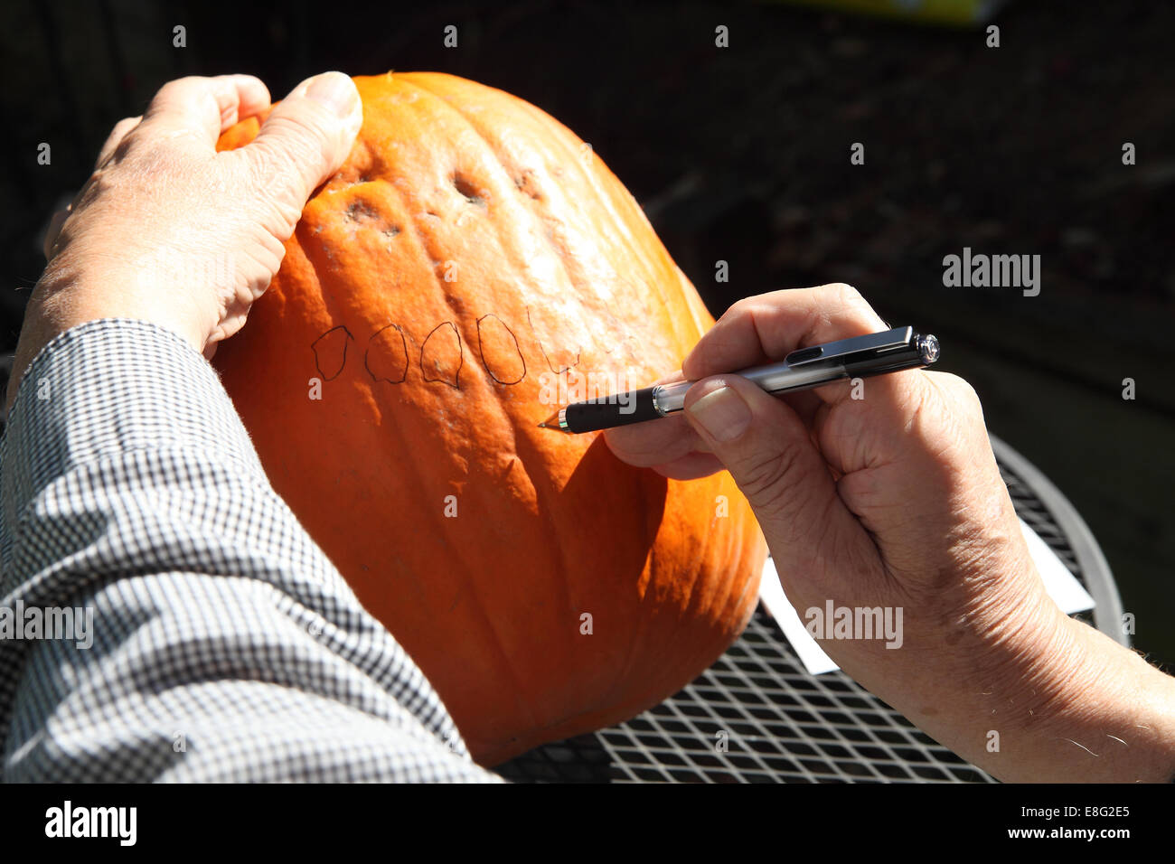 Ein Mann beginnt, ein originelles Design für einen Jack o' Lantern zu schaffen. Stockfoto