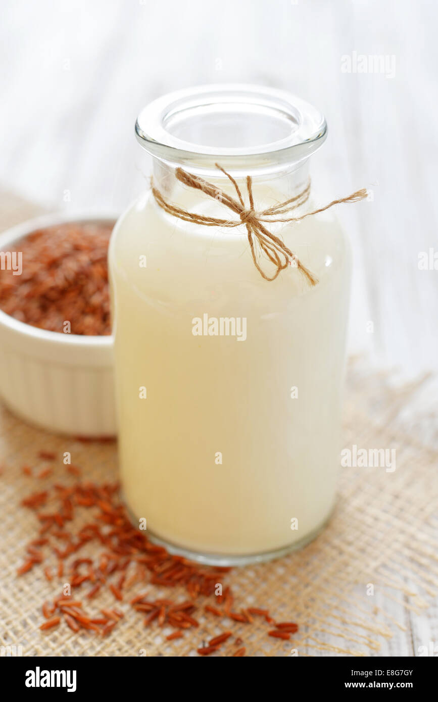 Reismilch in der Flasche auf weißem Hintergrund aus Holz. Vegane und vegetarische Milch-Konzept. Stockfoto