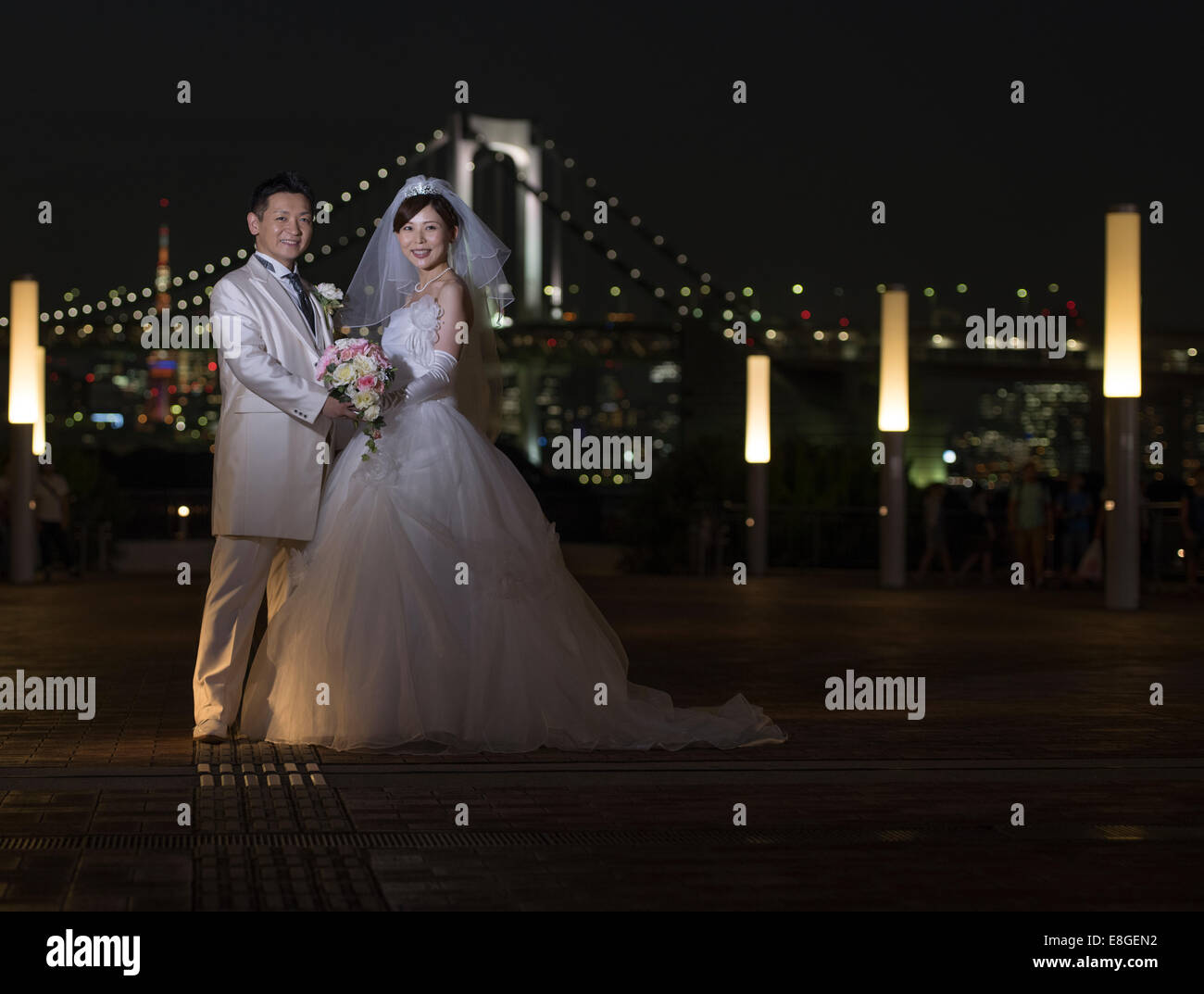 Braut und Bräutigam posieren für Fotos vor der Rainbow Bridge und Tokyo Tower, Odaiba, Tokyo, Japan. Stockfoto