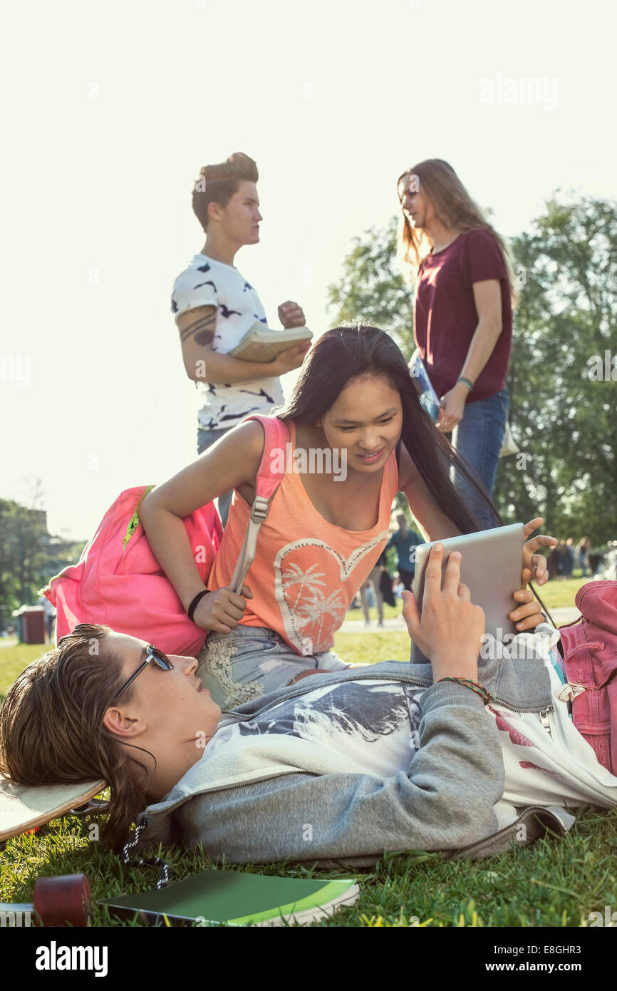 College-Student mit digital-Tablette am Schulhof mit Freunden im Gespräch im Hintergrund Stockfoto