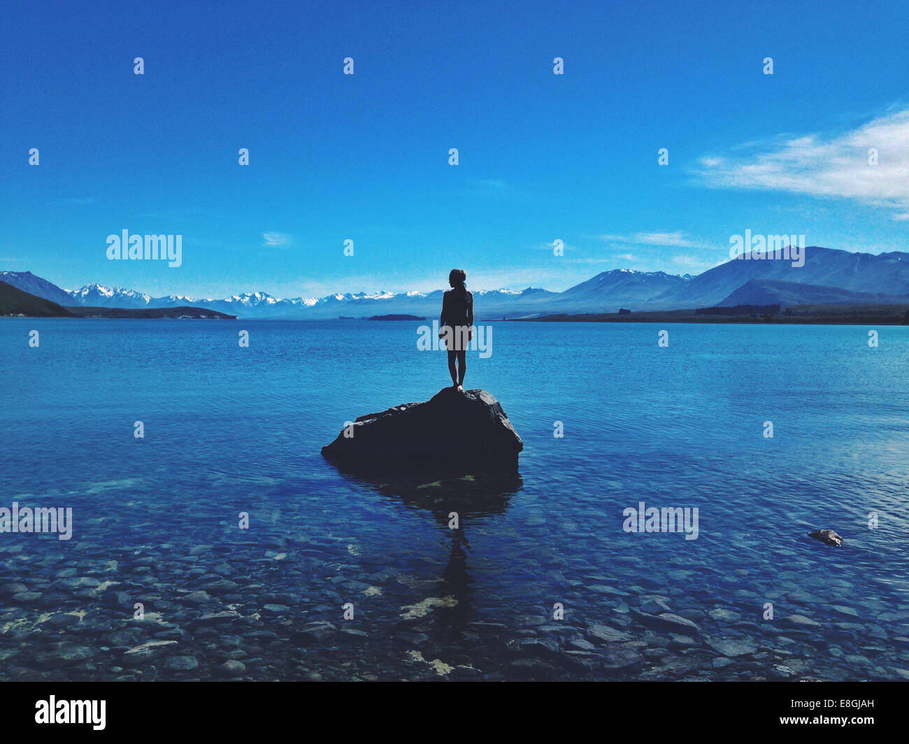 Frau steht auf einem Felsen, Lake Tekapo, Canterbury, Neuseeland Stockfoto