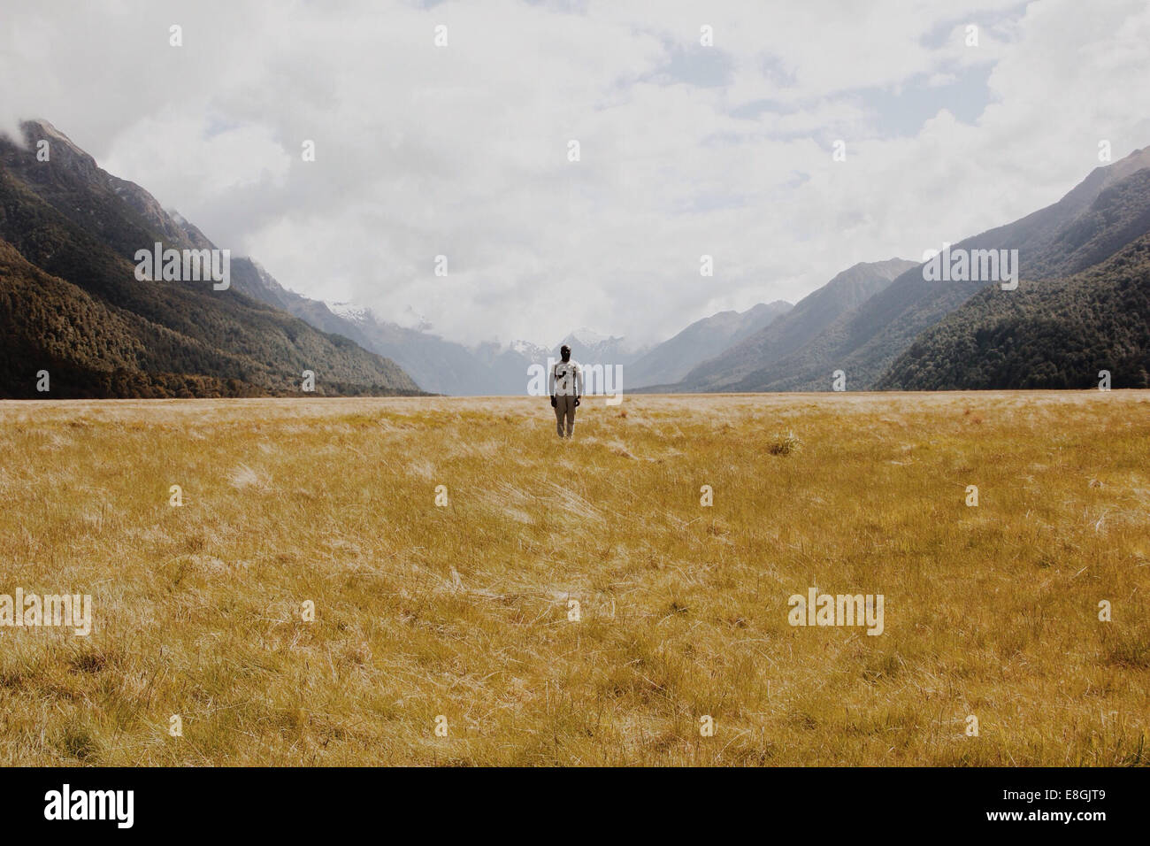 Neuseeland, Mann stand auf Wiese, Berge im Hintergrund Stockfoto