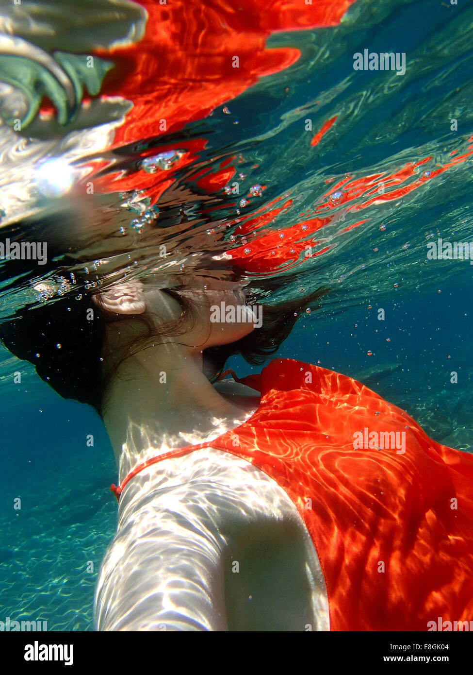 Nahaufnahme einer Frau in einem Kleid, die unter Wasser schwimmt, Sounion, Lavreotiki, Griechenland Stockfoto