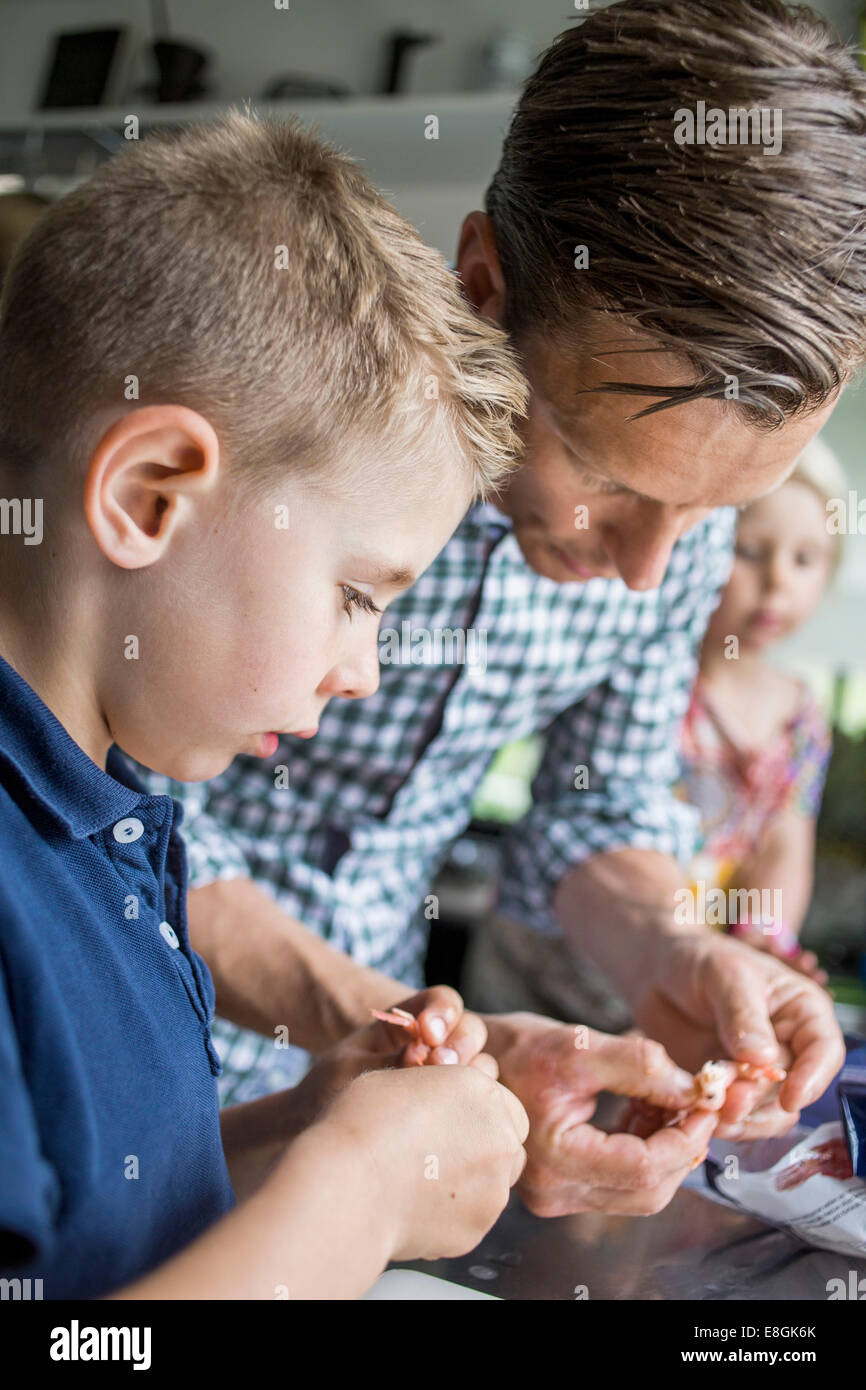 Vater und Sohn Reinigung Garnelen in Küche Stockfoto