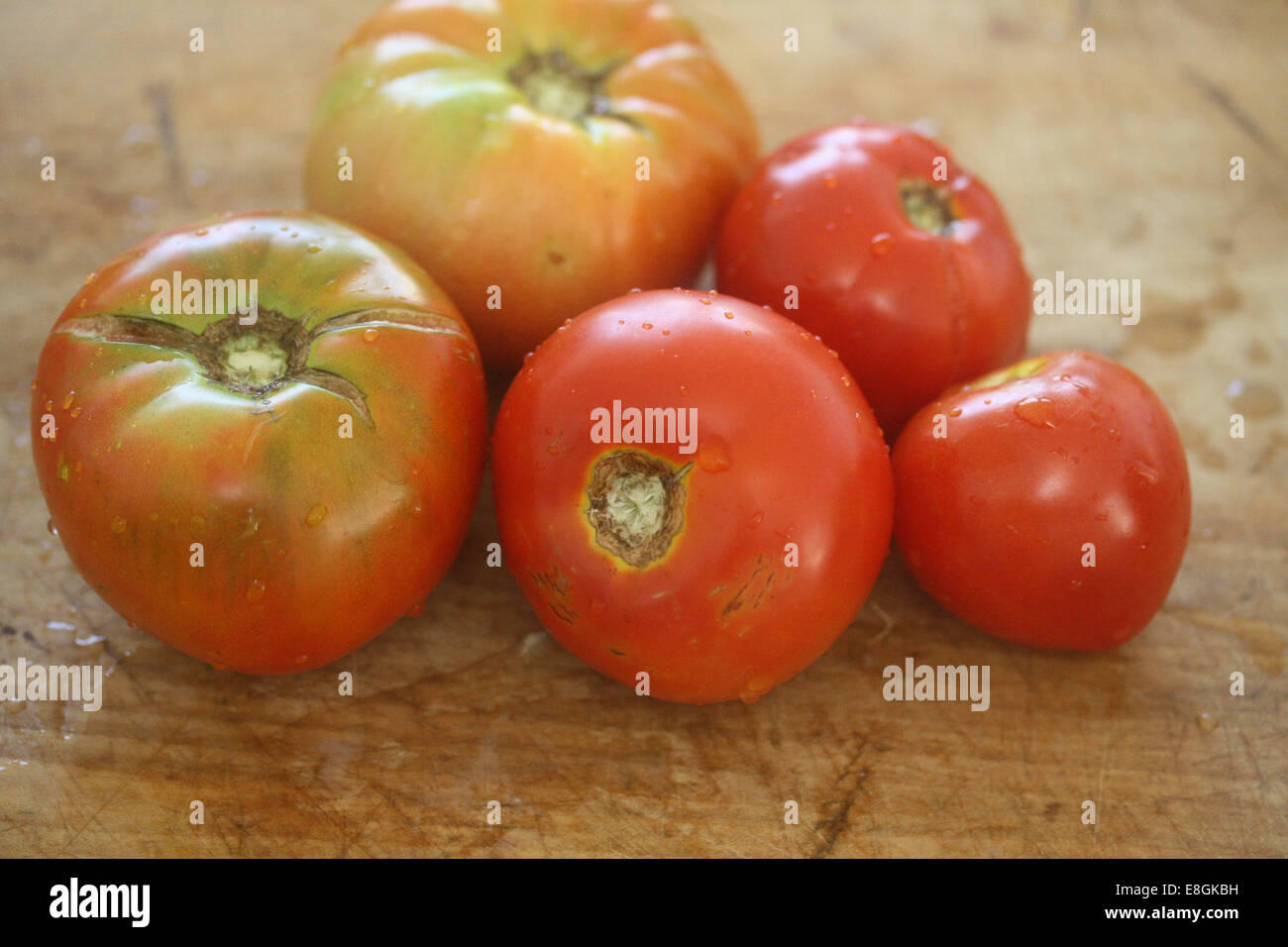 Fünf Heirloom Tomatoes auf Schneidbrett aus Holz Stockfoto