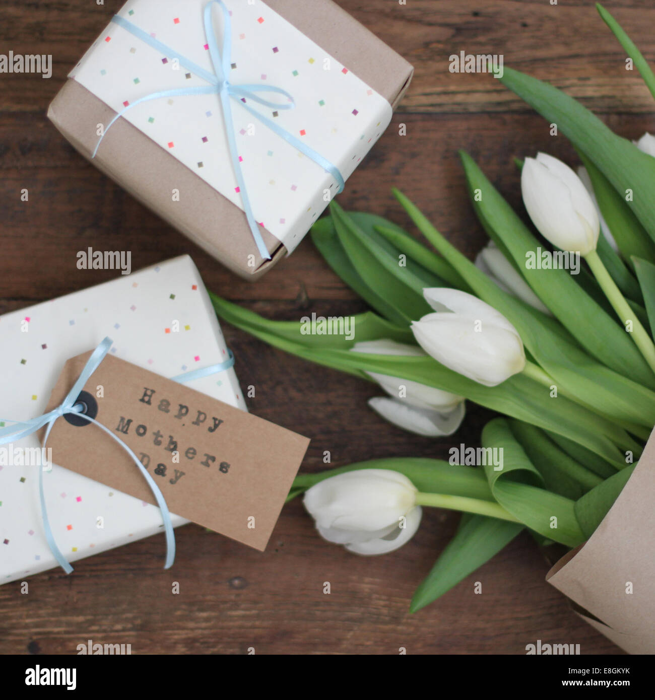 Ansicht von oben auf einen Haufen weißer Tulpen und eingewickelte Muttertagsgeschenke auf einen Tisch Stockfoto