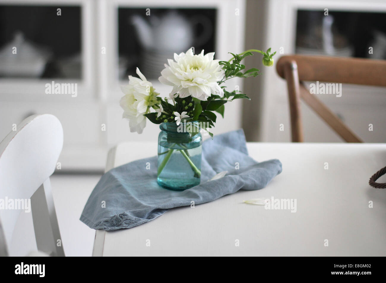 Vase mit Blumen und Serviette auf Esstisch Stockfoto