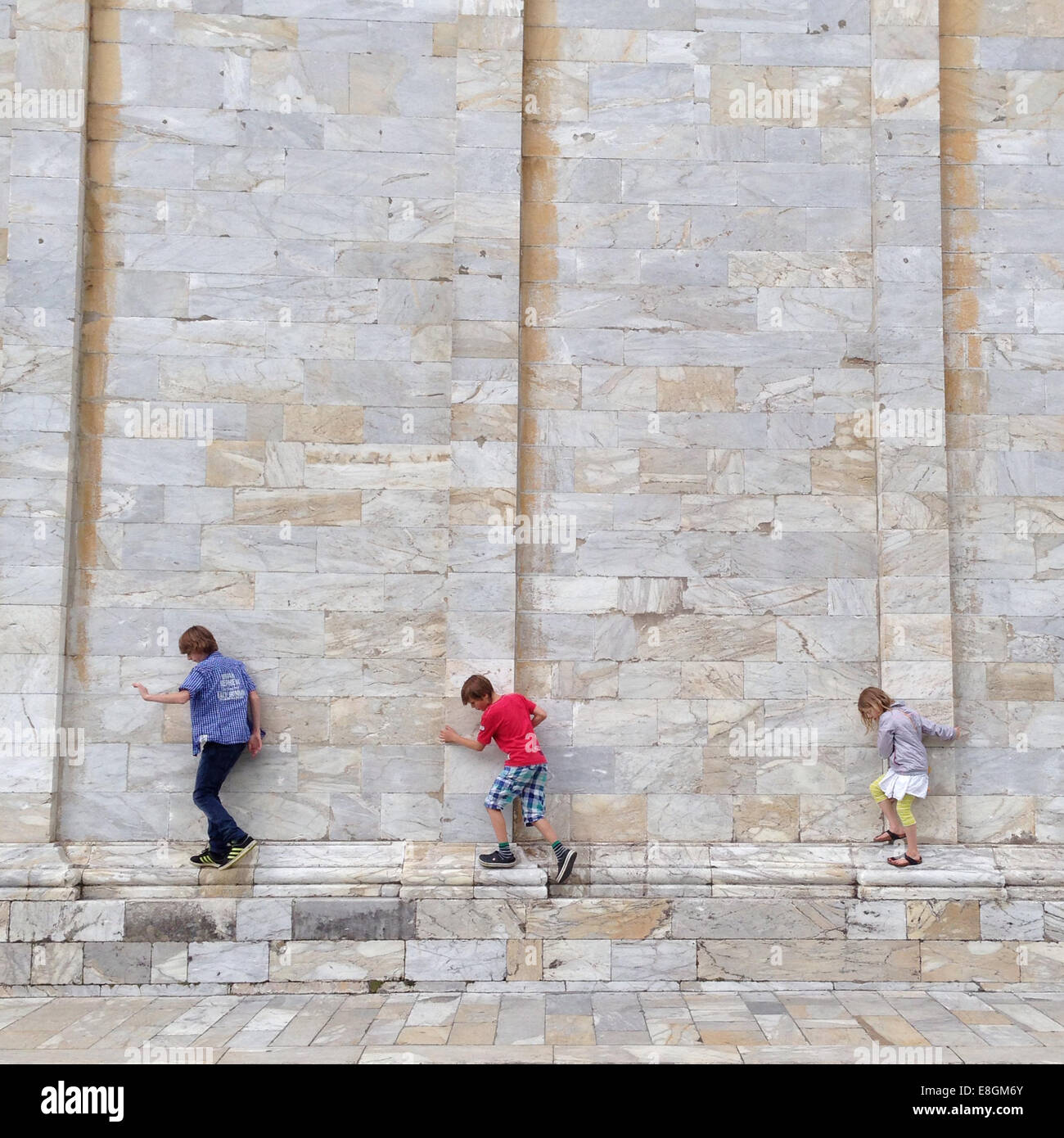 Drei Kinder, die an einer Ziegelmauer entlang gehen, Pisa, Toskana, italien Stockfoto