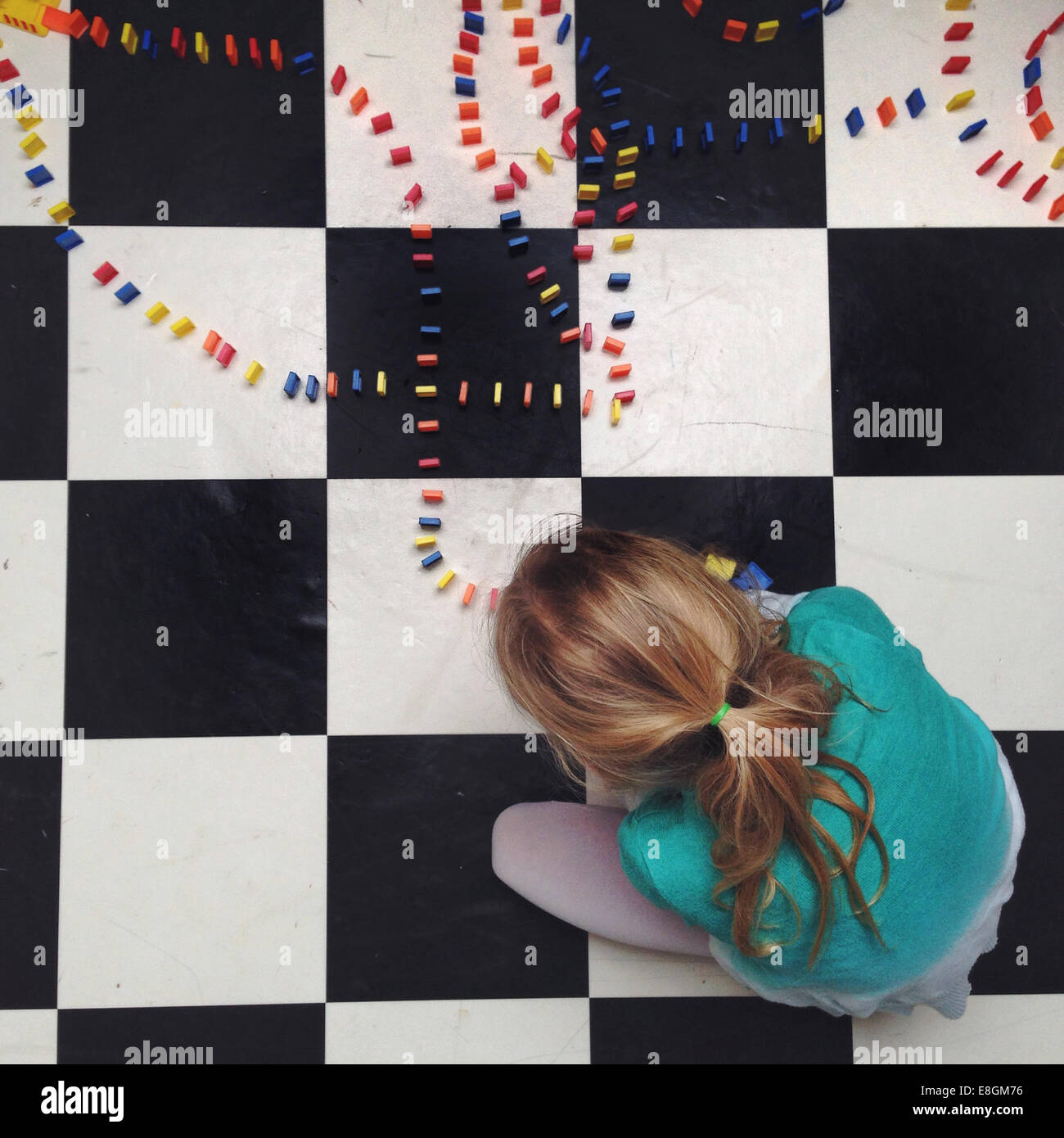 Mädchen sitzt auf dem Boden Einrichten Linien von Dominos Stockfoto