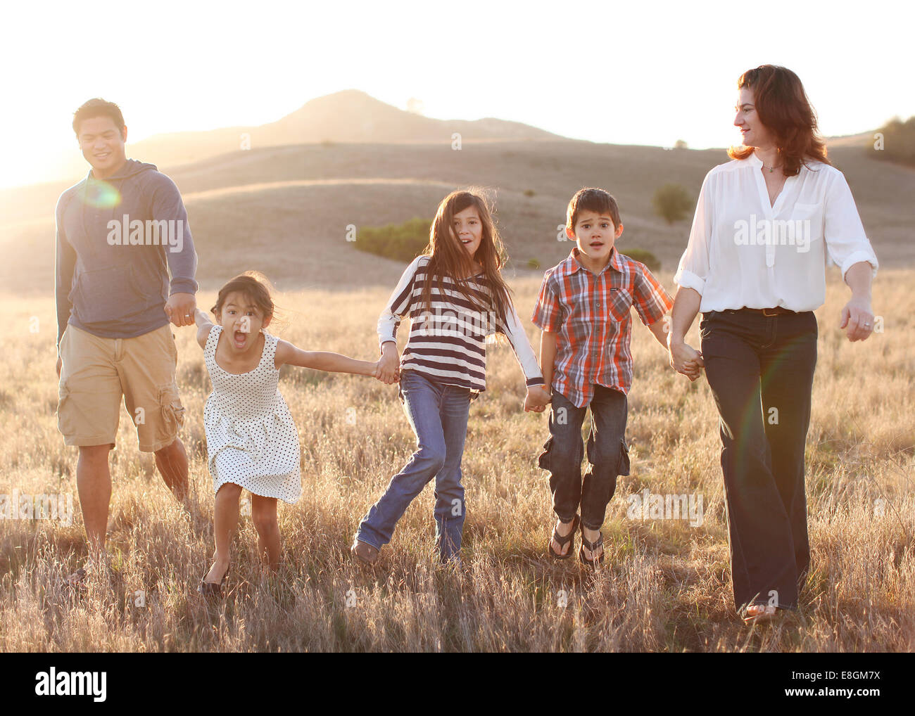 Fünfköpfige Familie Hand in Hand, Wandern in Wiese Stockfoto
