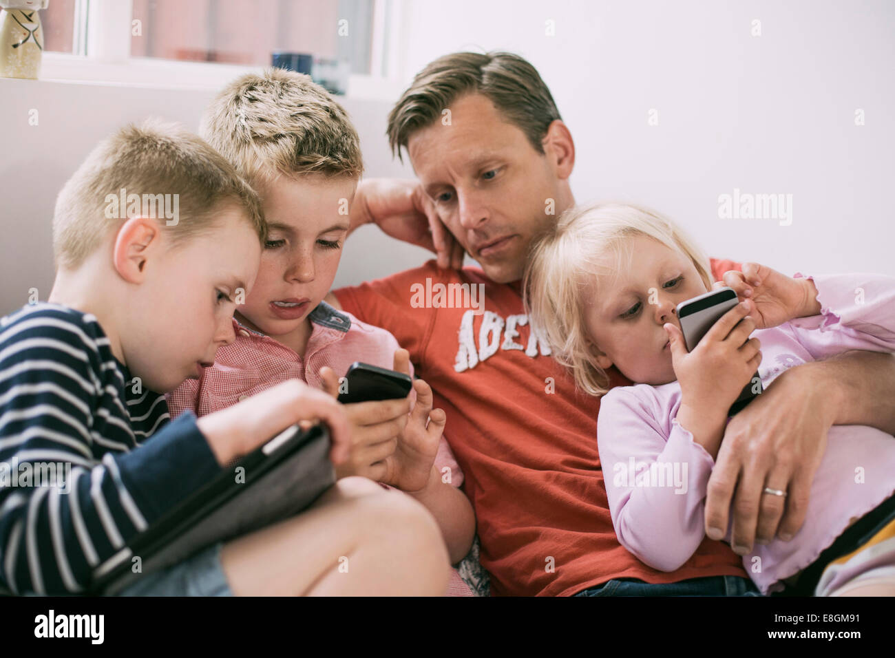 Vater und Kinder bei der Nutzung von Technologien zu Hause Stockfoto