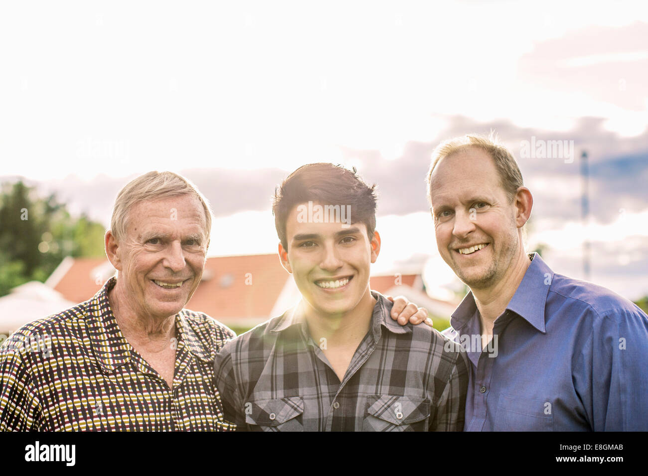 Porträt von drei Generationen männlichen Familie lächelnd gegen Himmel Stockfoto