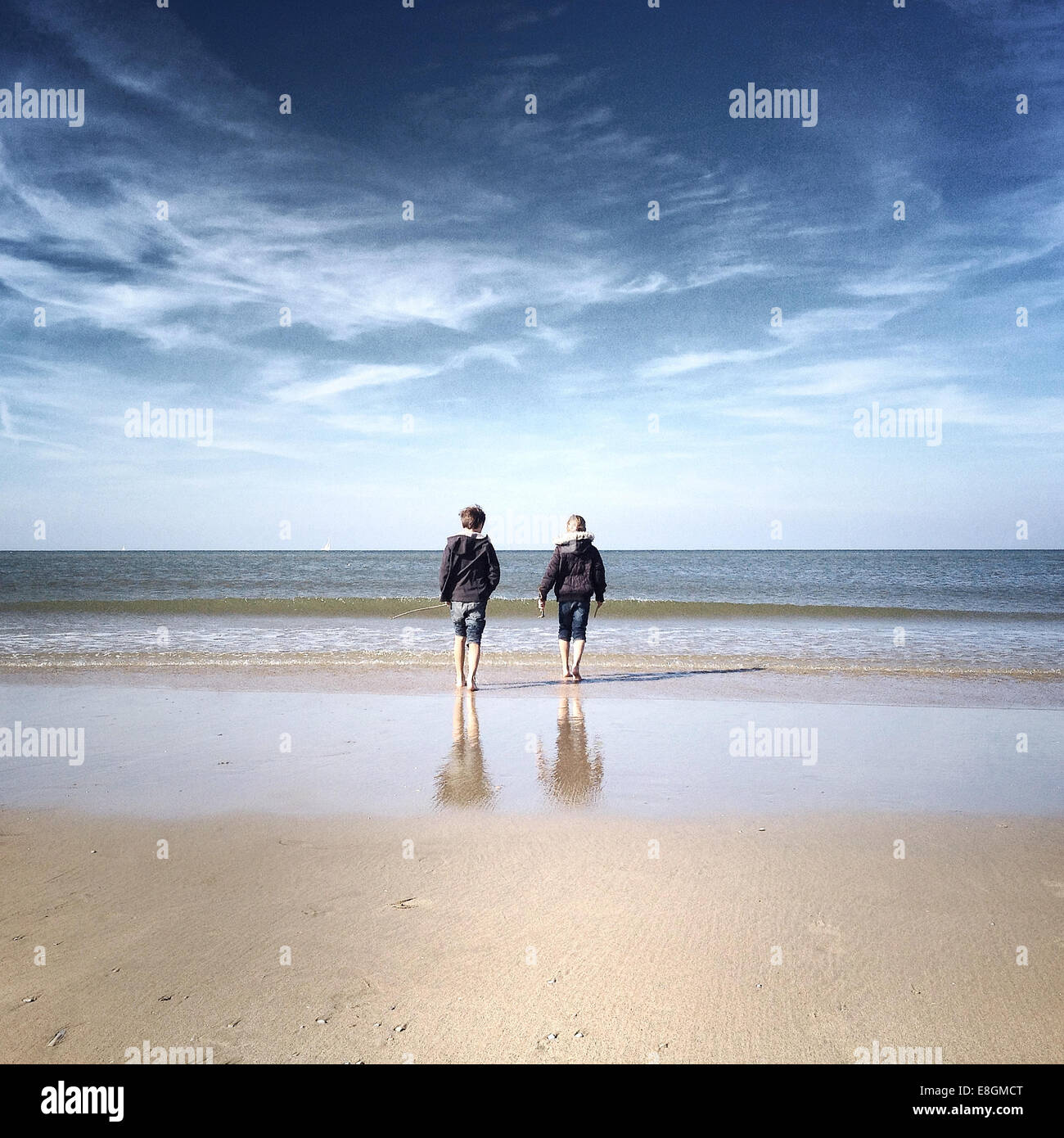 Rückansicht von zwei Kindern, die am Strand spazieren Stockfoto