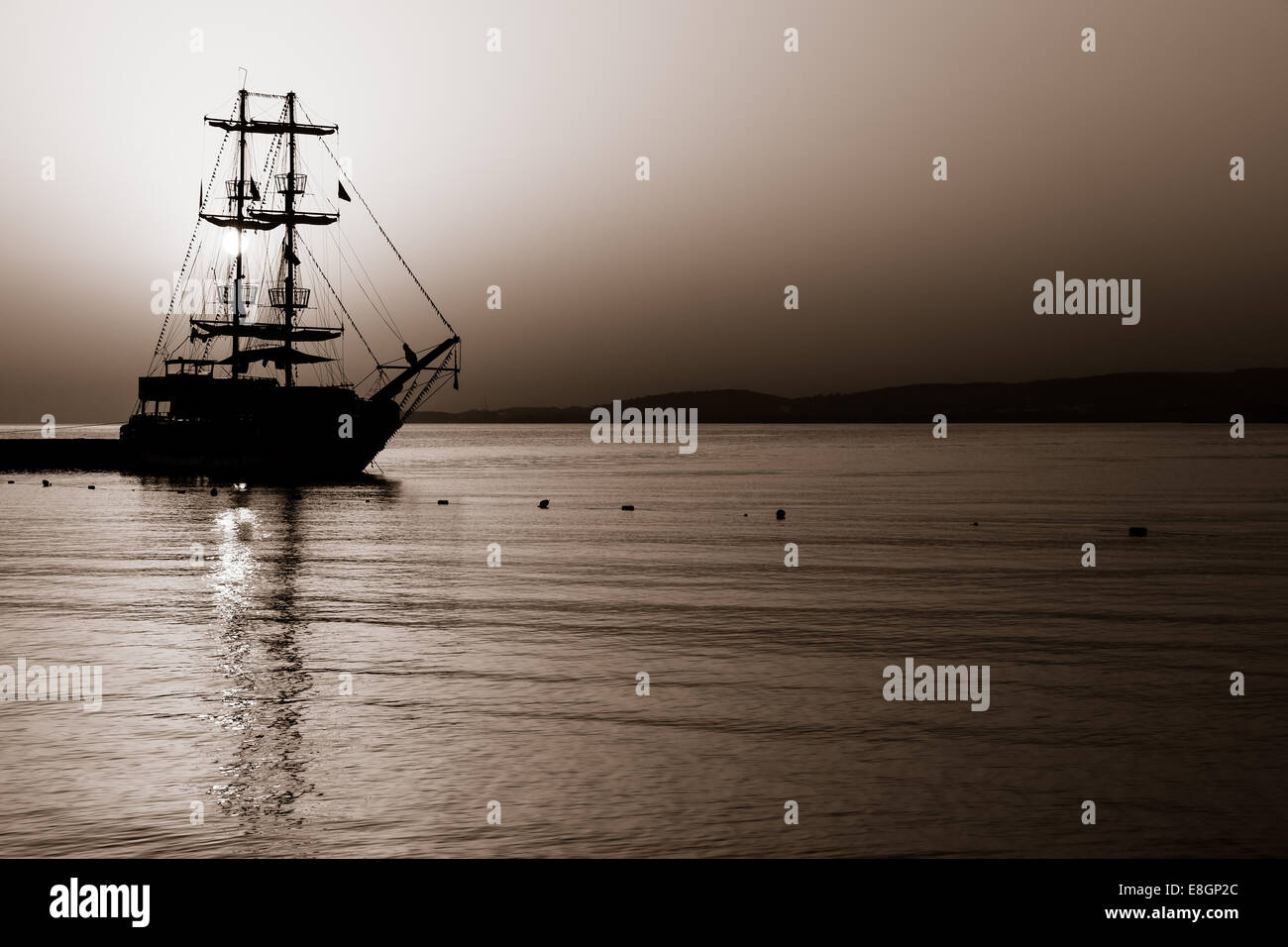 Sonnenuntergang über dem Meer. Segelschiff in der Bucht. Tonen. Stilisierung. Stockfoto