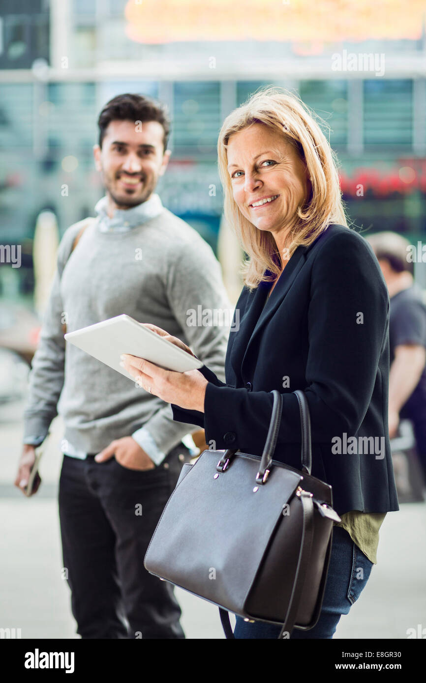 Porträt der Geschäftsfrau mit digital-Tablette auf Stadtstraße mit Kollegen im Hintergrund Stockfoto