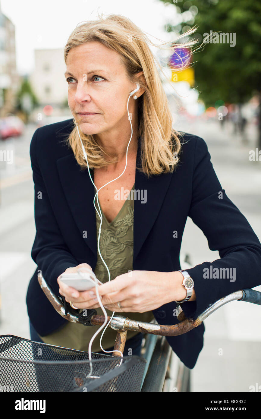 Geschäftsfrau Musik hören über Smartphone und stützte sich auf dem Fahrrad im freien Stockfoto